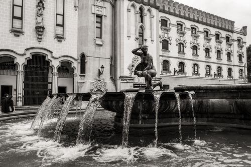 Free Black and white image of a classic fountain with an ornate building in Madrid, Spain. Stock Photo