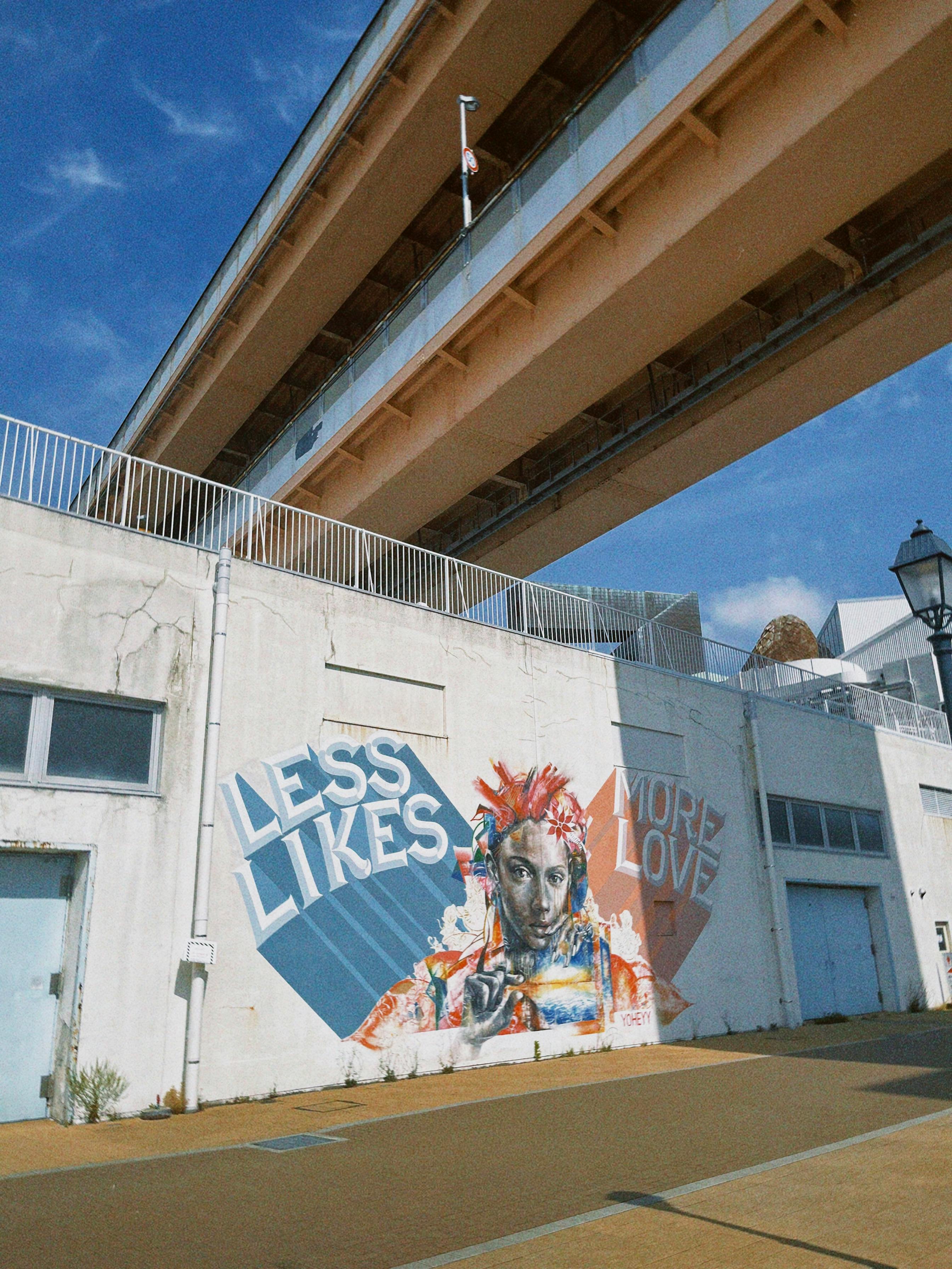 Kostenlos Farbenfrohe Straßenkunst mit der Botschaft „Weniger Likes, mehr Liebe“ unter einer Brücke in Kobe, Japan. Stock-Foto