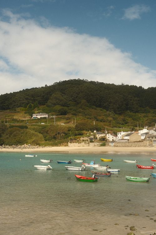 Free Discover the tranquil beauty of Galicia's coast with colorful boats gently floating in a serene bay. Stock Photo