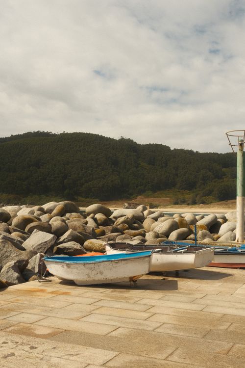 Free Peaceful coastal scene with small boats and rocky shoreline in Galicia, Spain. Stock Photo