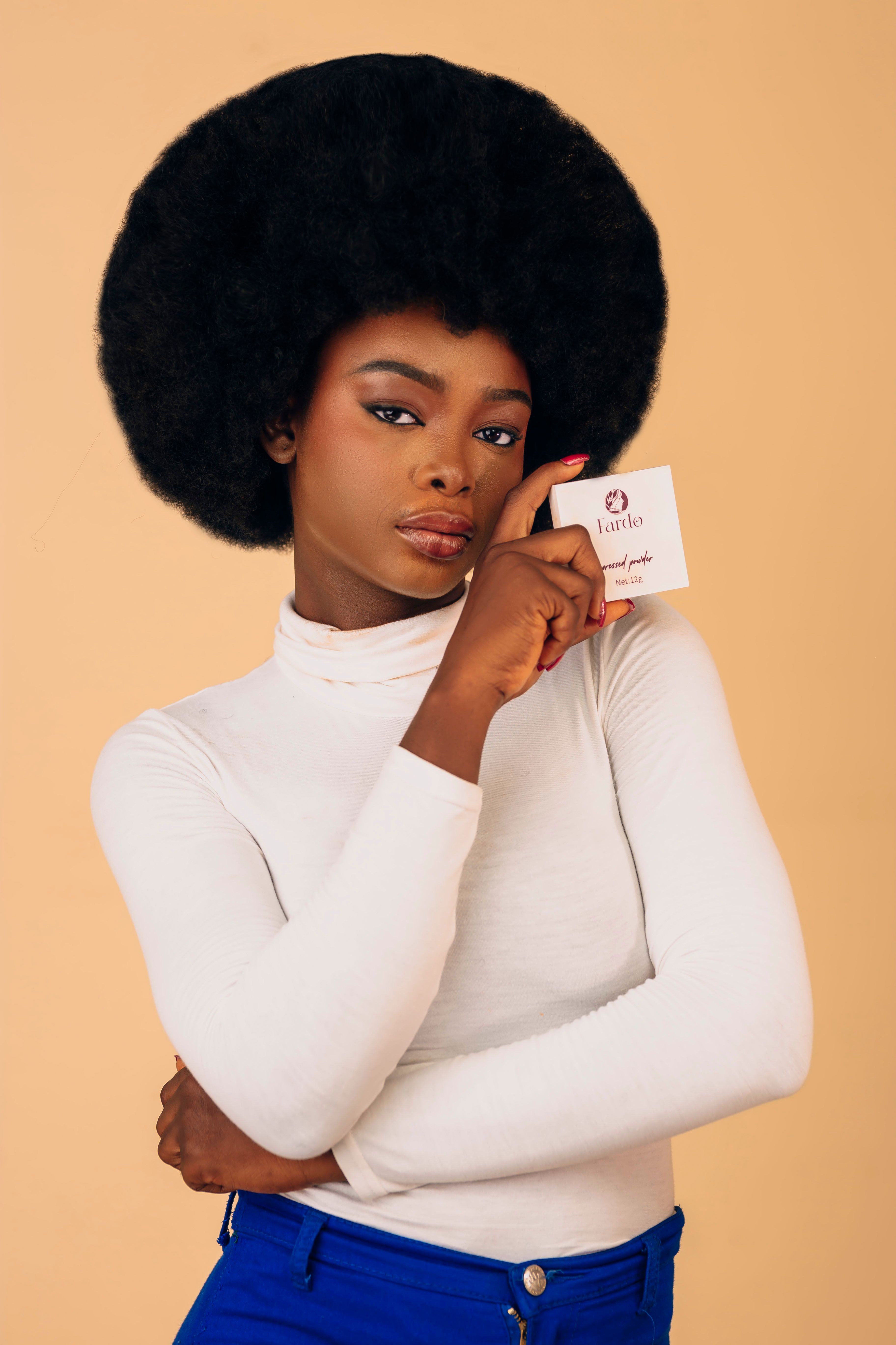 Elegant woman with afro hairstyle holding a card. Fashionable studio portrait.