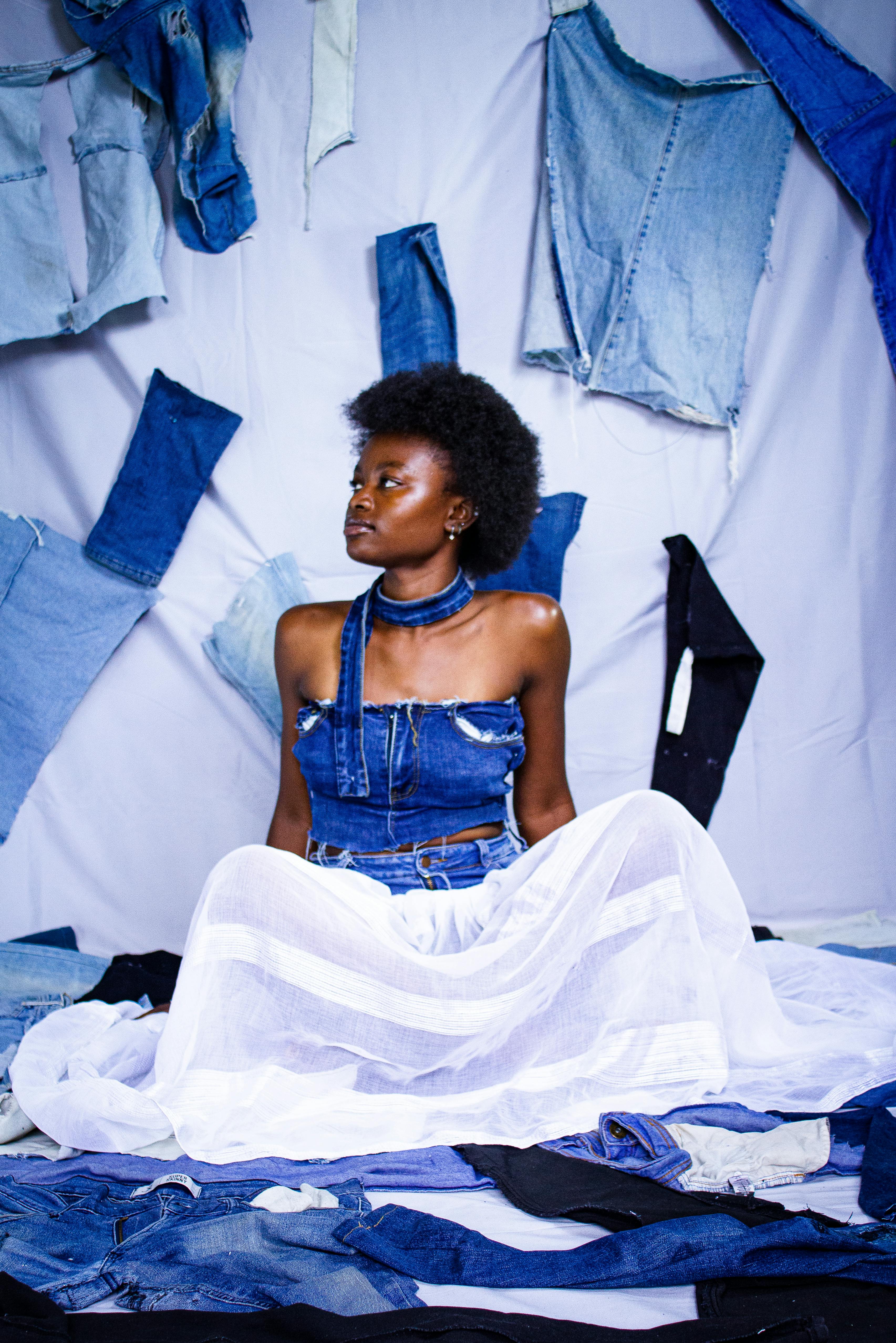 Portrait of a stylish woman in denim fashion surrounded by vibrant fabric elements.