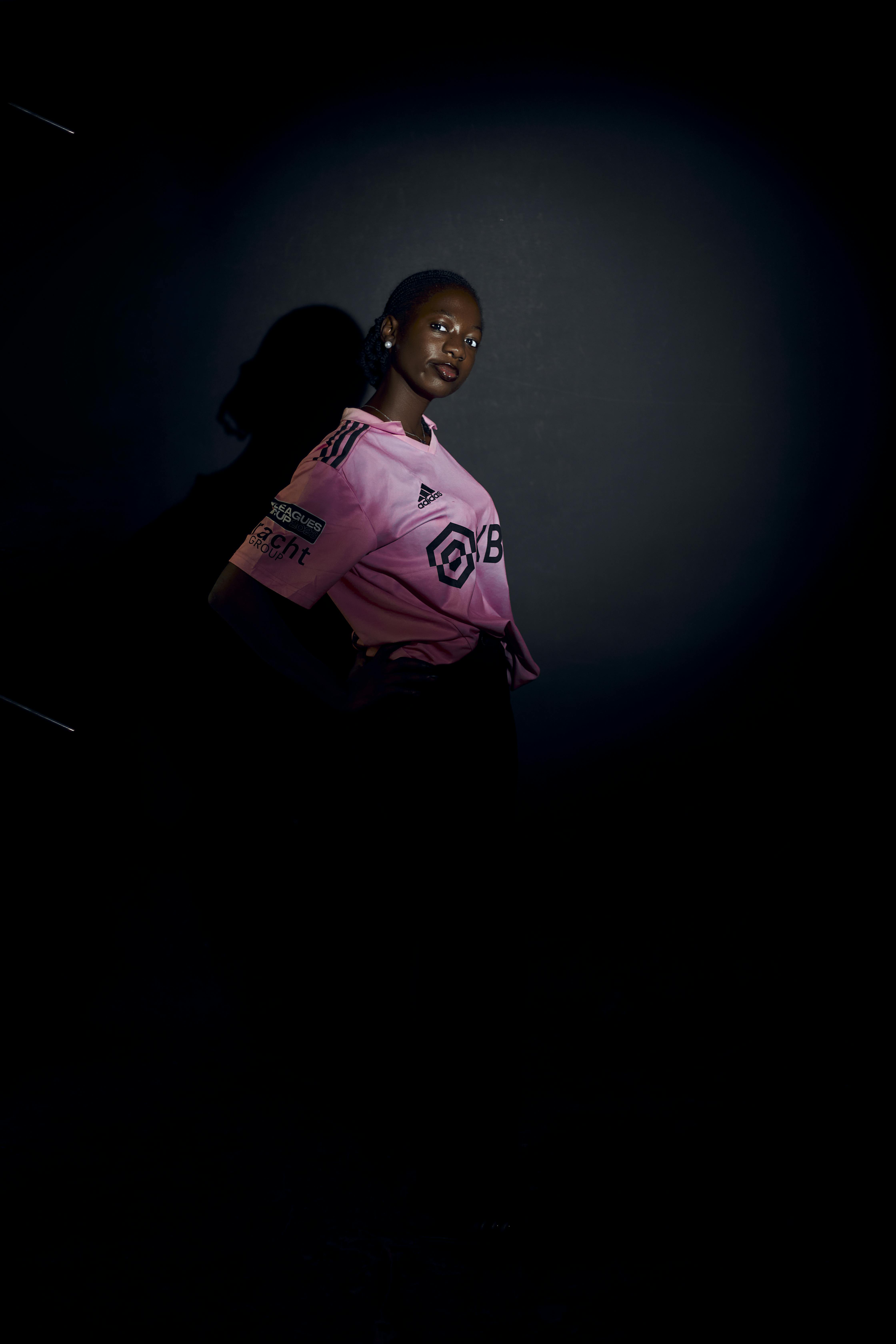 Gratuit Portret sumbru al unei femei într-un tricou sport roz, cu iluminare dramatică. Fotografie de stoc