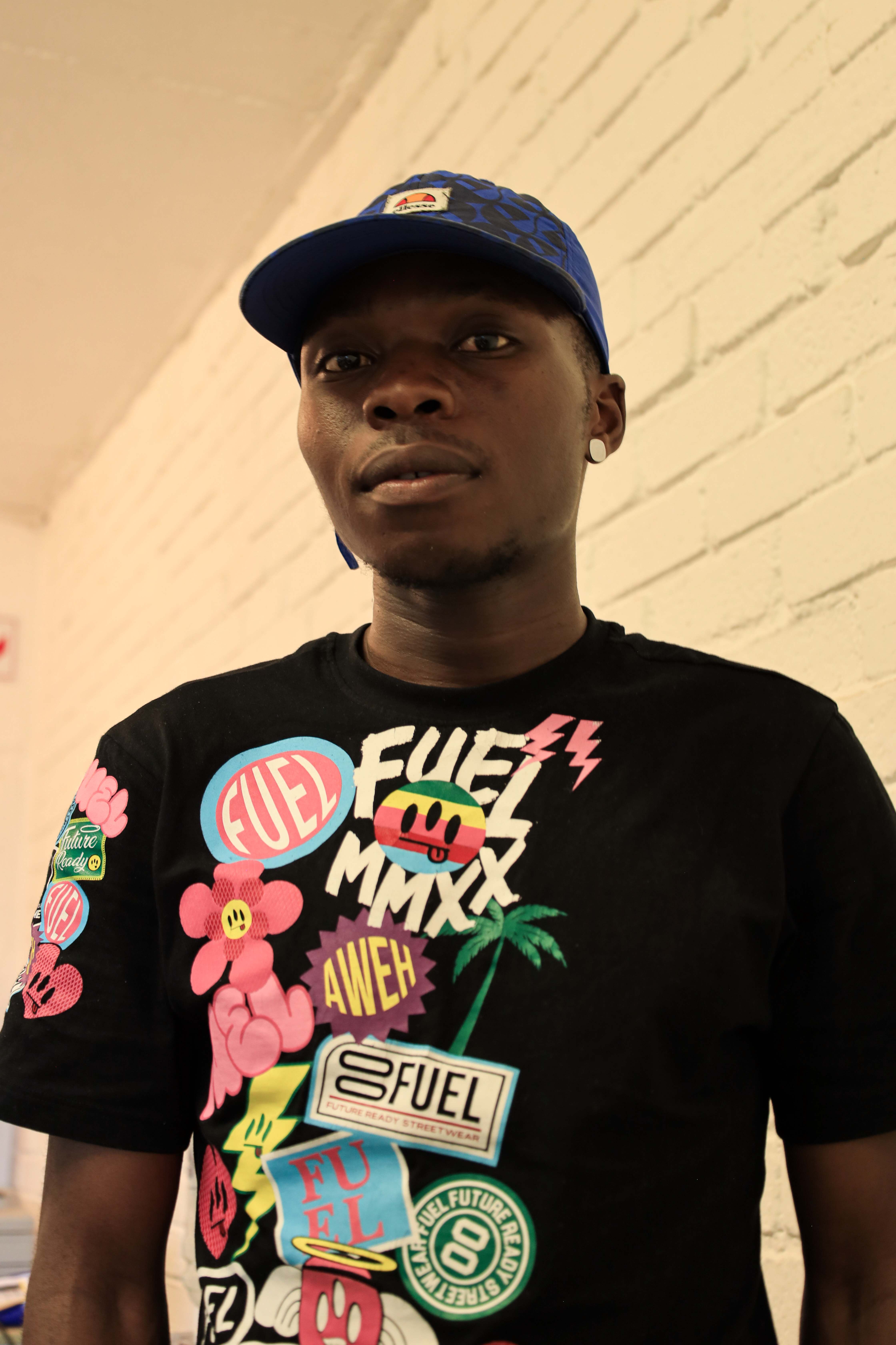 Young adult in vibrant urban fashion with logo designs, indoors in Randburg.