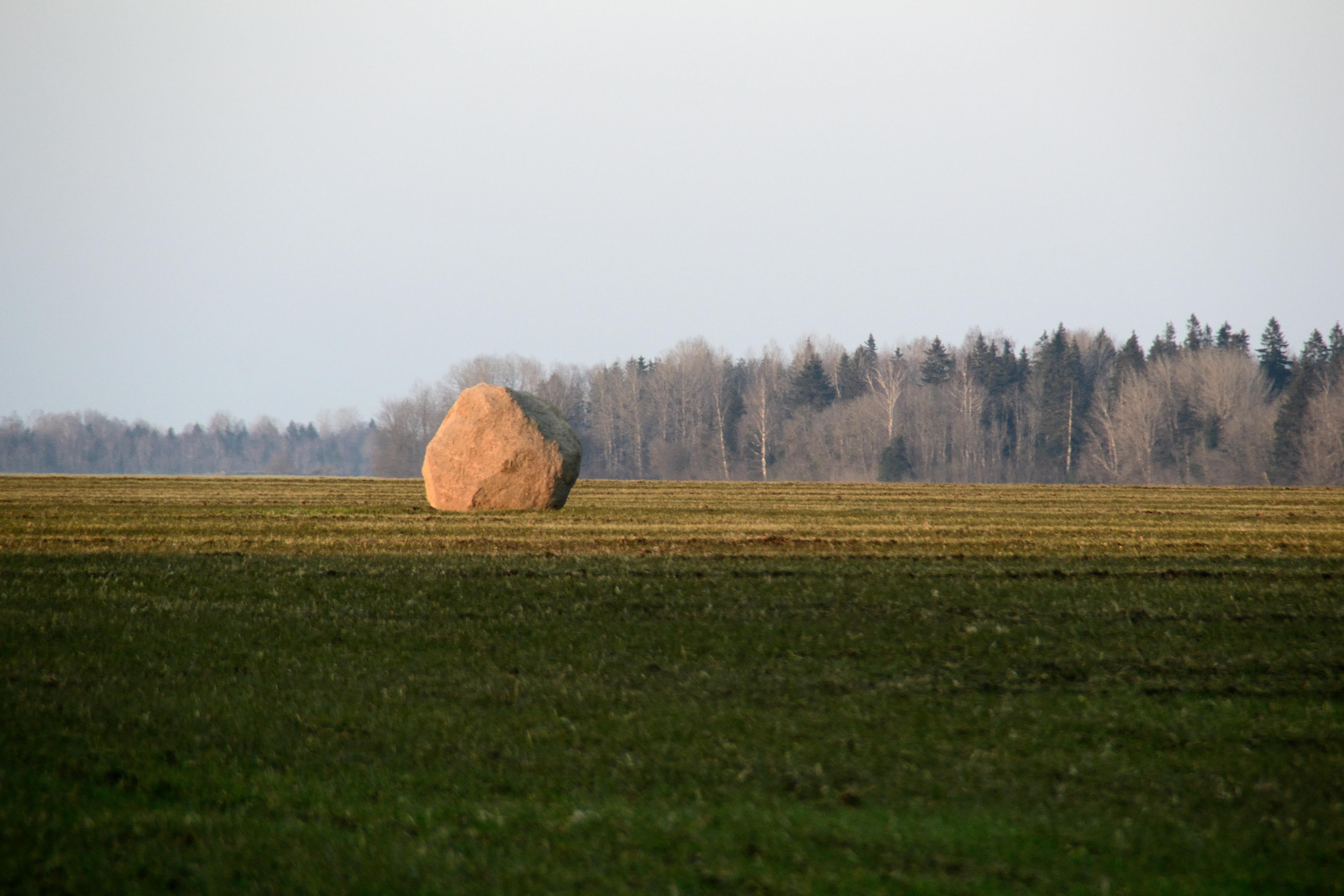 Gratis Un paisaje sereno que presenta una gran roca solitaria en un campo abierto bajo un cielo despejado al anochecer. Foto de stock