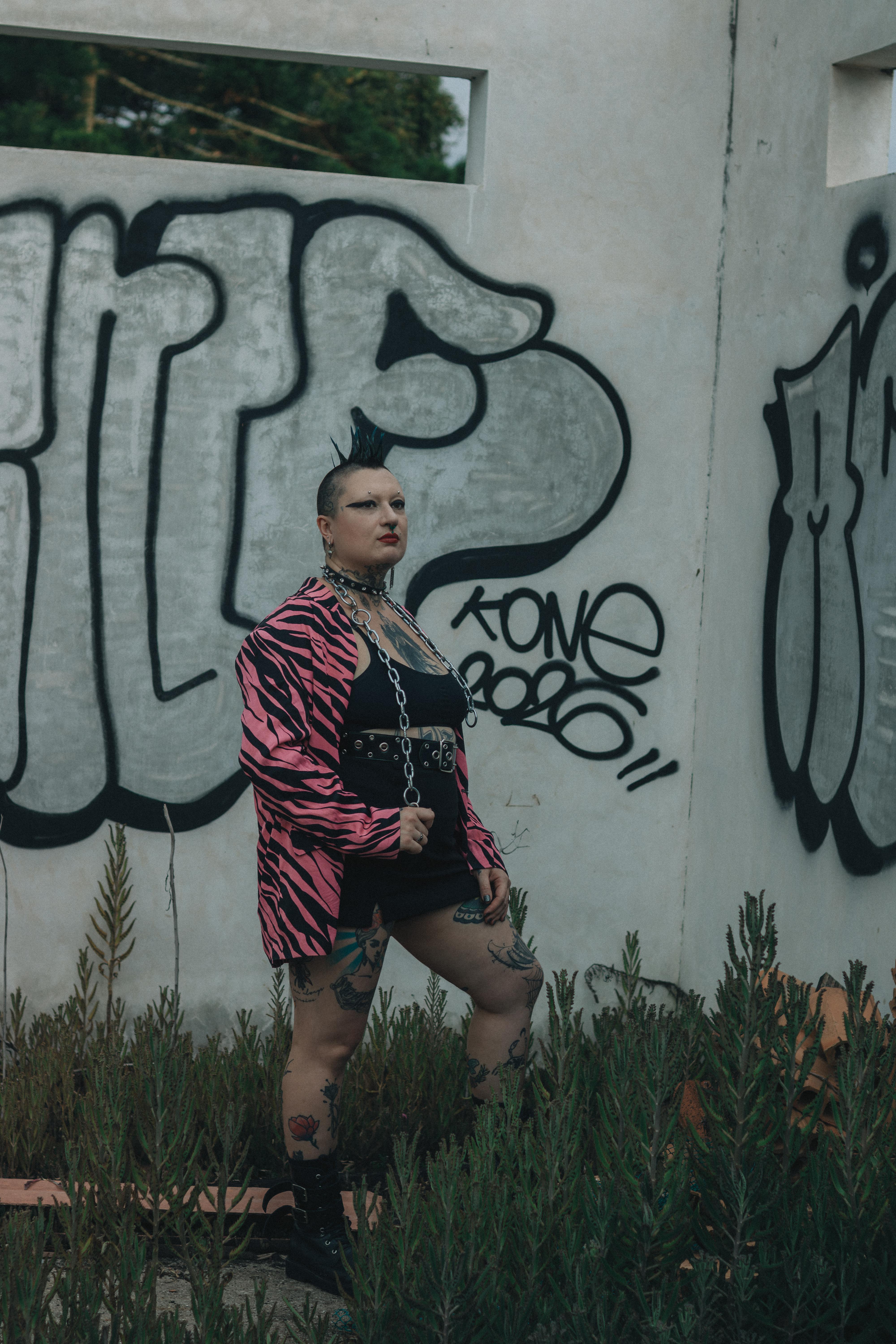 Kostenlos Ausdrucksstarkes Modeporträt einer Person vor einer Graffiti-Wand, das Streetstyle ausstrahlt. Stock-Foto