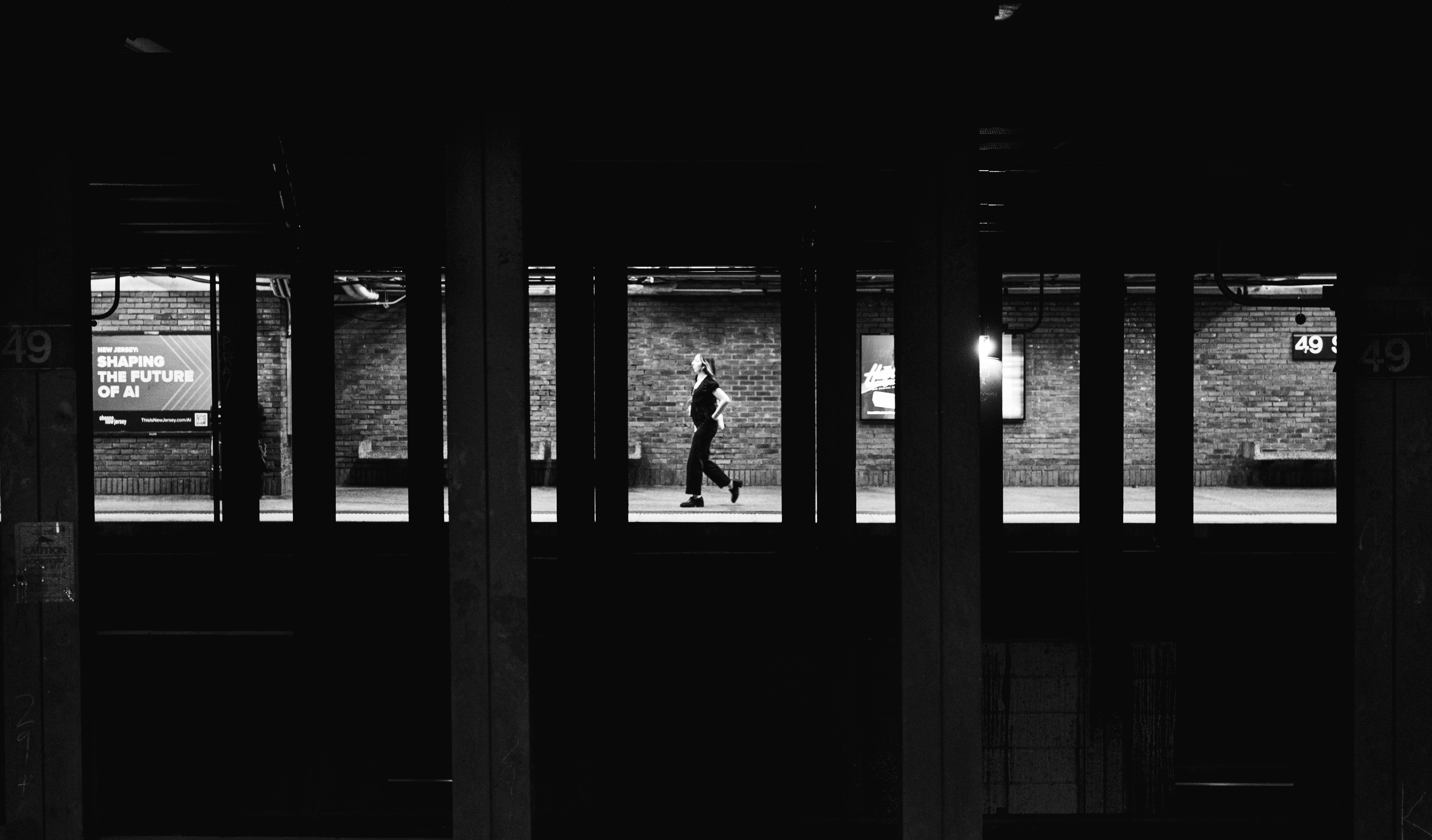 bezplatná Dramatická černobílá fotografie osamělého dojíždějícího ve stanici newyorského metra. Základová fotografie