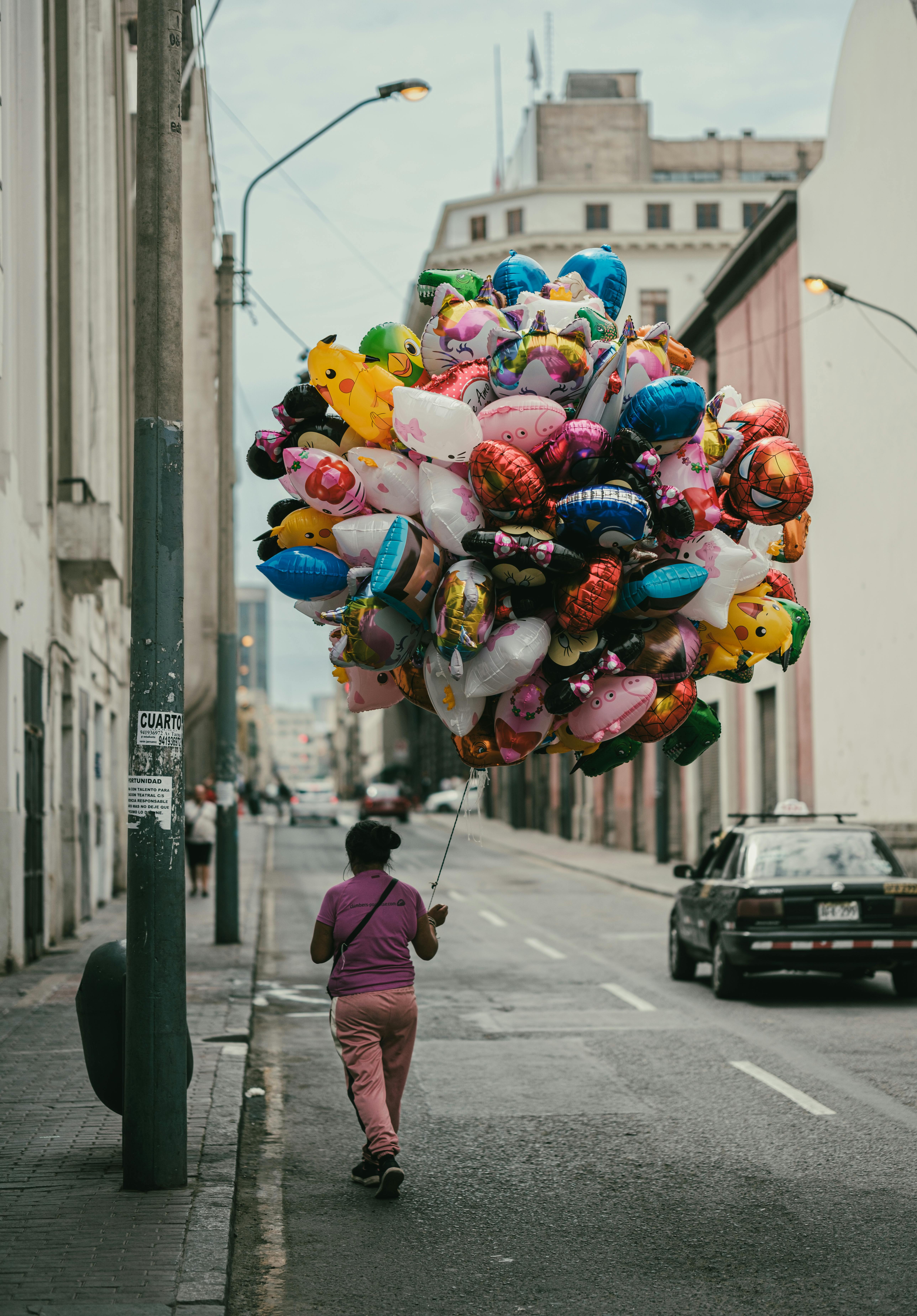 Vibrant balloons carried by a vendor on an urban street in Lima, Peru, showcasing local street life.