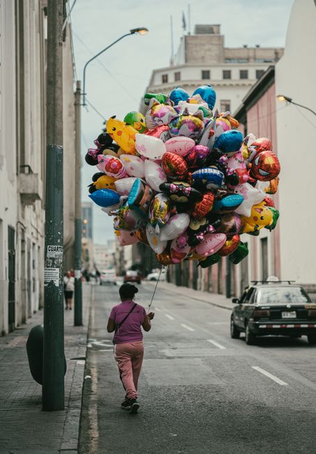 Vibrant balloons carried by a vendor on an urban street in Lima, Peru, showcasing local street life.