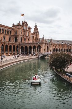 Rowboat on the canal at Plaza de España in Seville, Spain, showcasing stunning architecture.