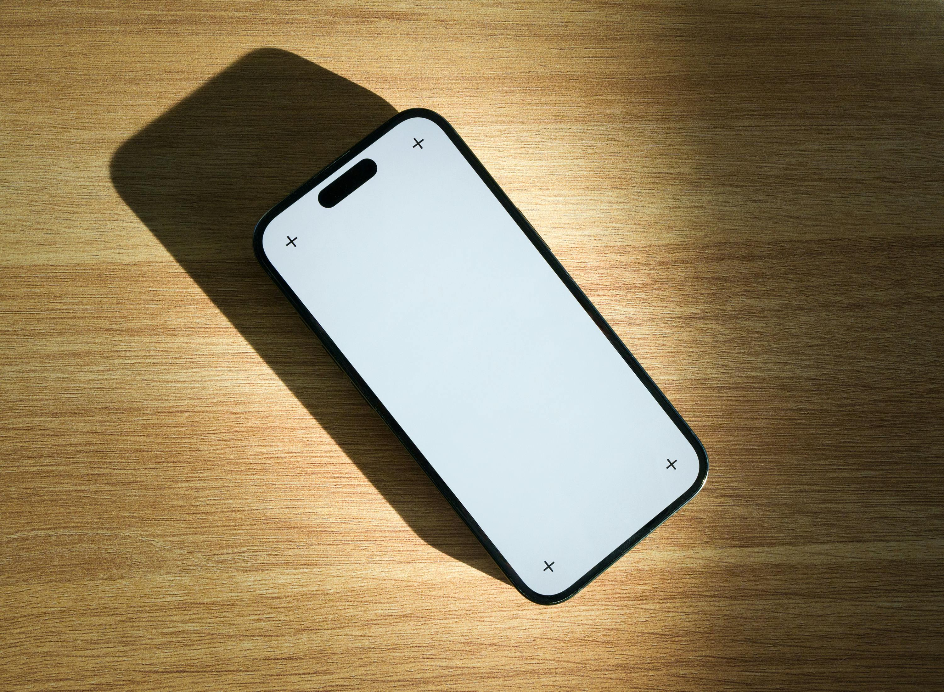 Gratuit Un smartphone élégant à écran vierge posé sur une table en bois, idéal pour les maquettes de design et les présentations technologiques. Photos