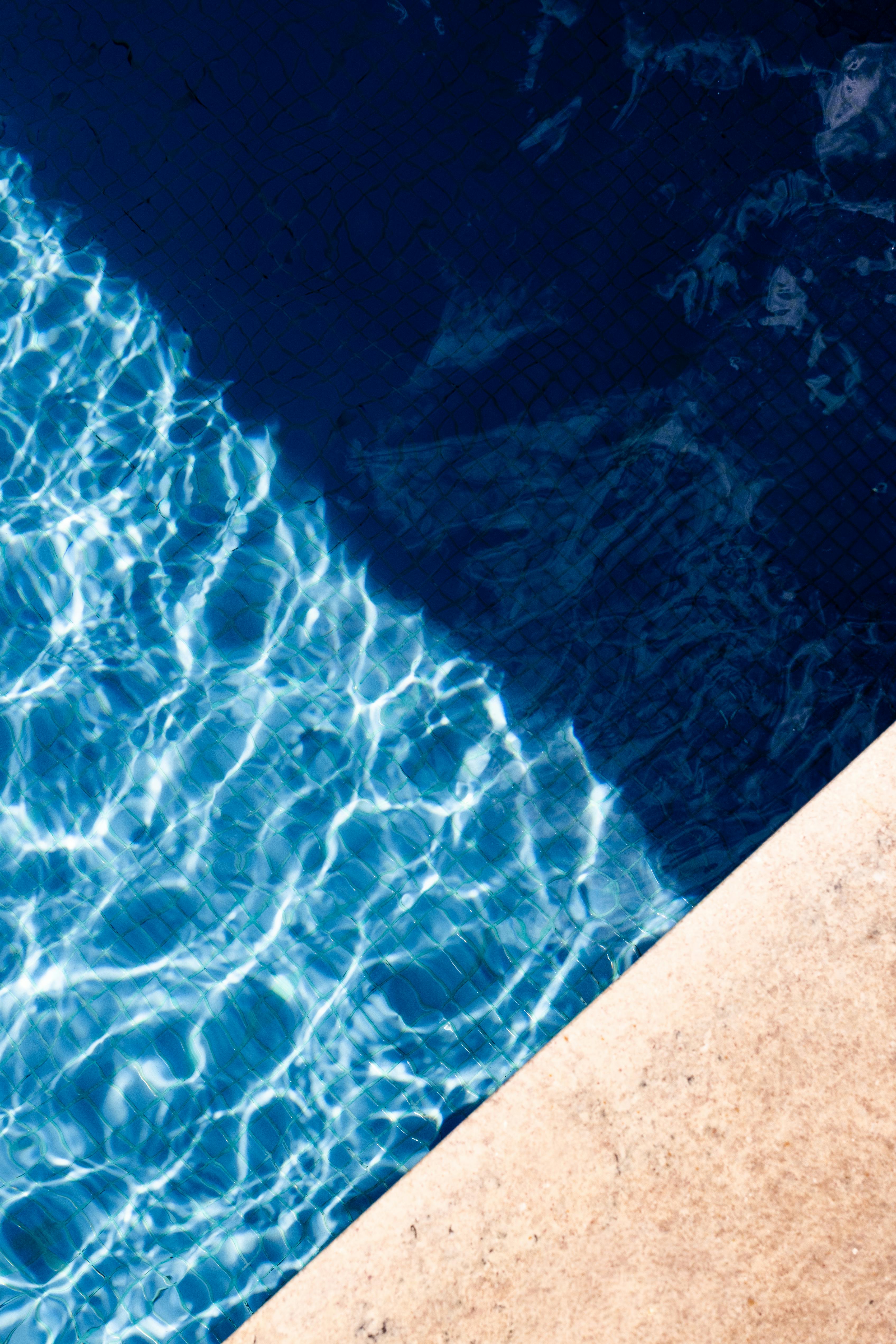 Kostenlos Das Sonnenlicht tanzt auf dem blauen Wasser des Pools und erzeugt faszinierende Wellenmuster, die perfekt zu sommerlichen Themen passen. Stock-Foto