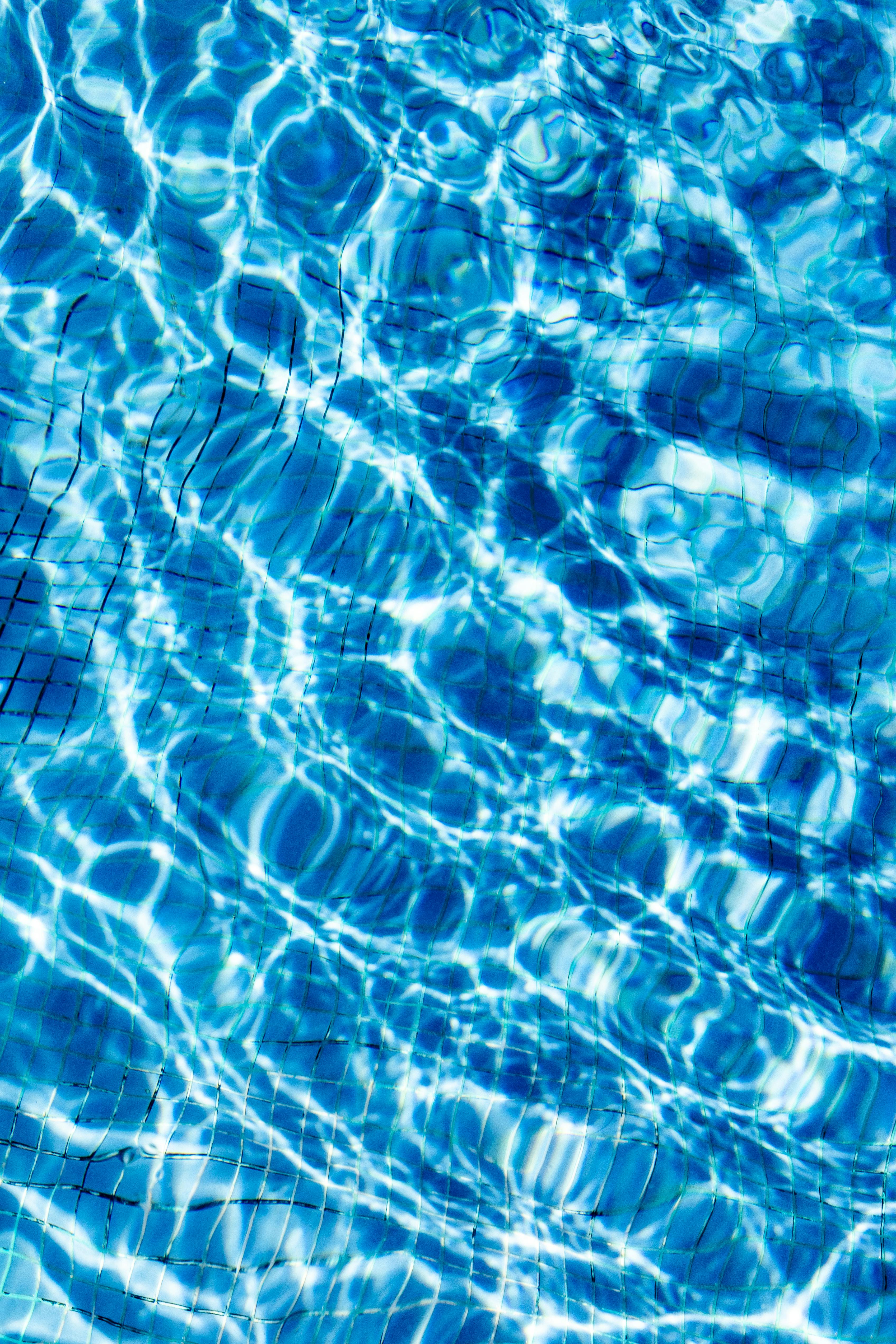 Gratuit Un prim-plan al reflexiilor dinamice ale soarelui care creează modele pe apa albastră limpede a piscinei, perfecte pentru fundaluri. Fotografie de stoc