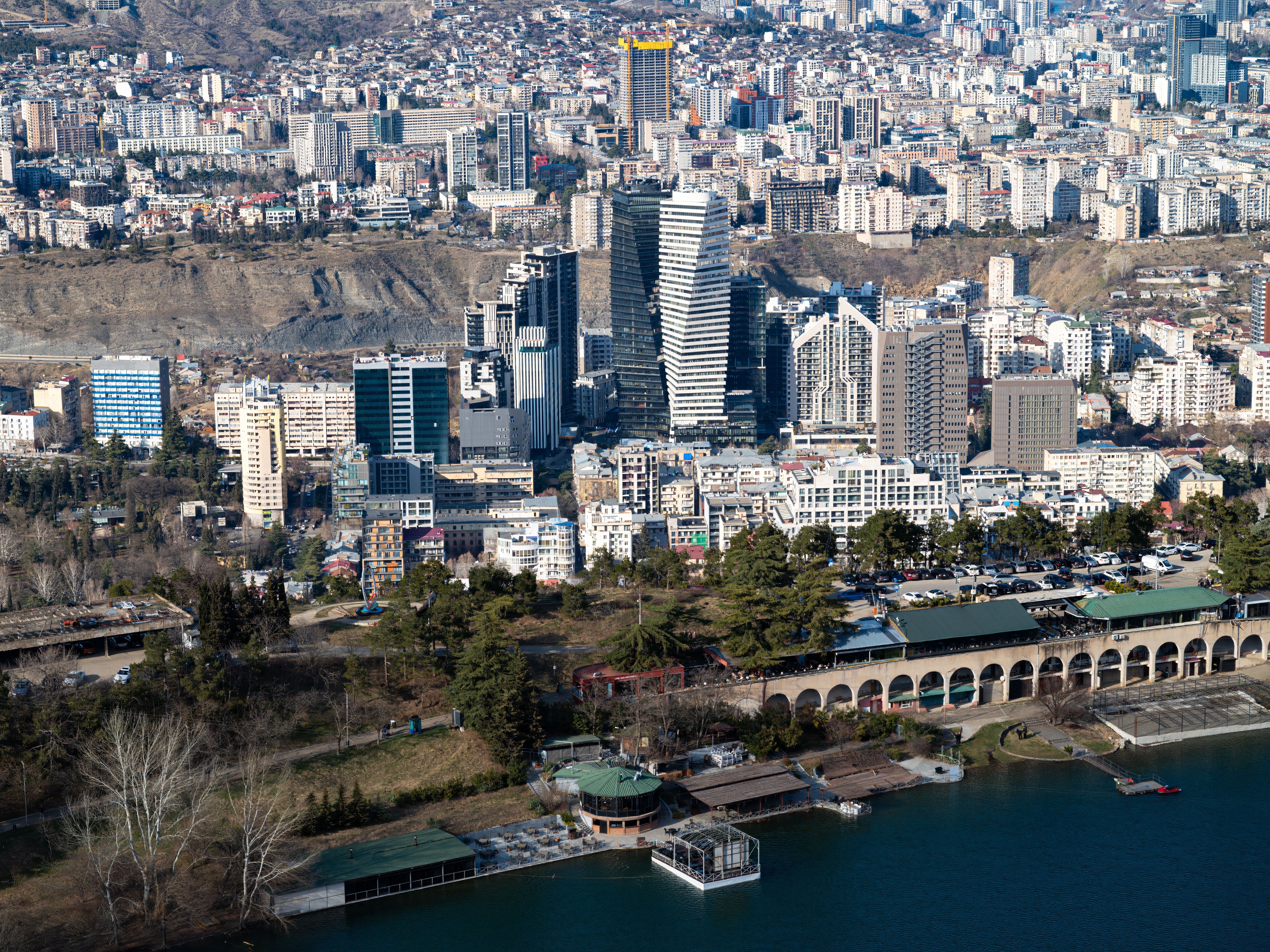 Aerial cityscape of Tbilisi featuring modern skyscrapers and waterfront view.