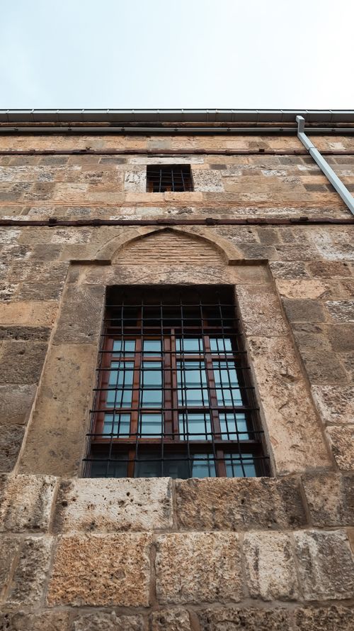 Free Close-up of a historic stone building in Konya, Türkiye, highlighting an iron-barred window with unique architectural details. Stock Photo