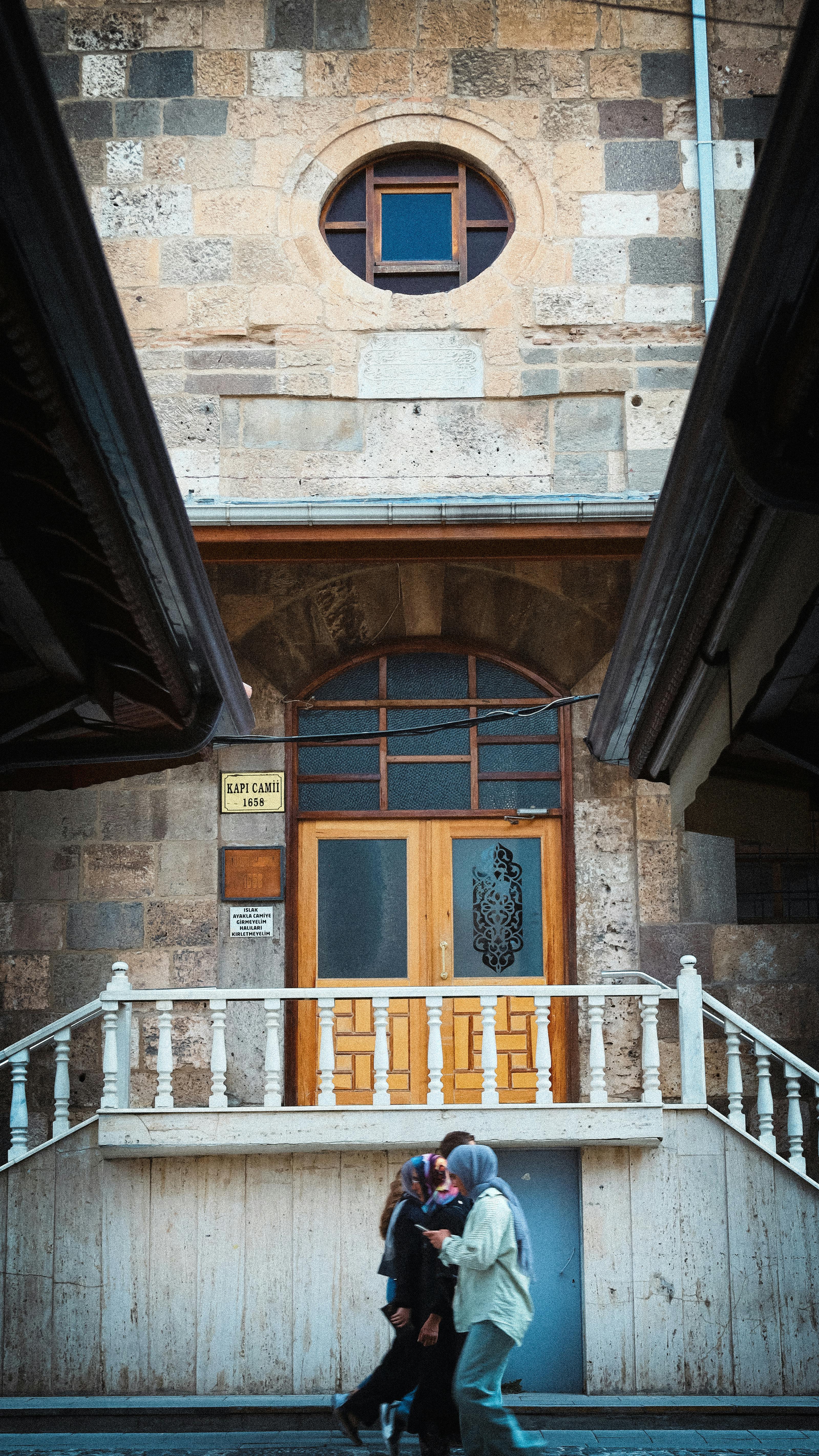 De franc Dues persones caminen per davant d'un edifici històric a Konya, Turquia, que exhibeix un disseny arquitectònic únic. Foto d'estoc