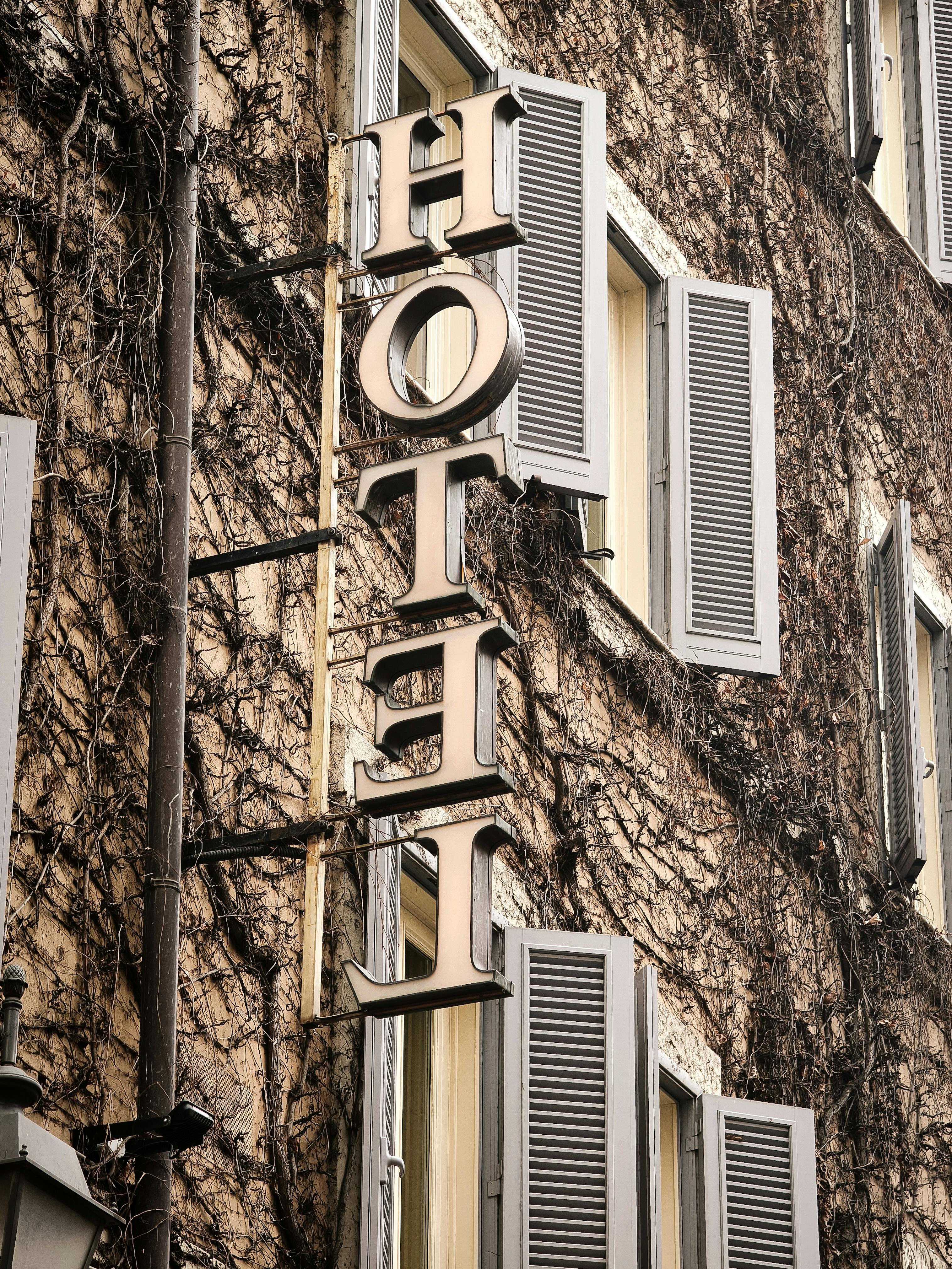 grátis Fachada de hotel em tons quentes coberta de hera, com detalhes arquitetônicos clássicos, em Roma, Itália. Foto profissional