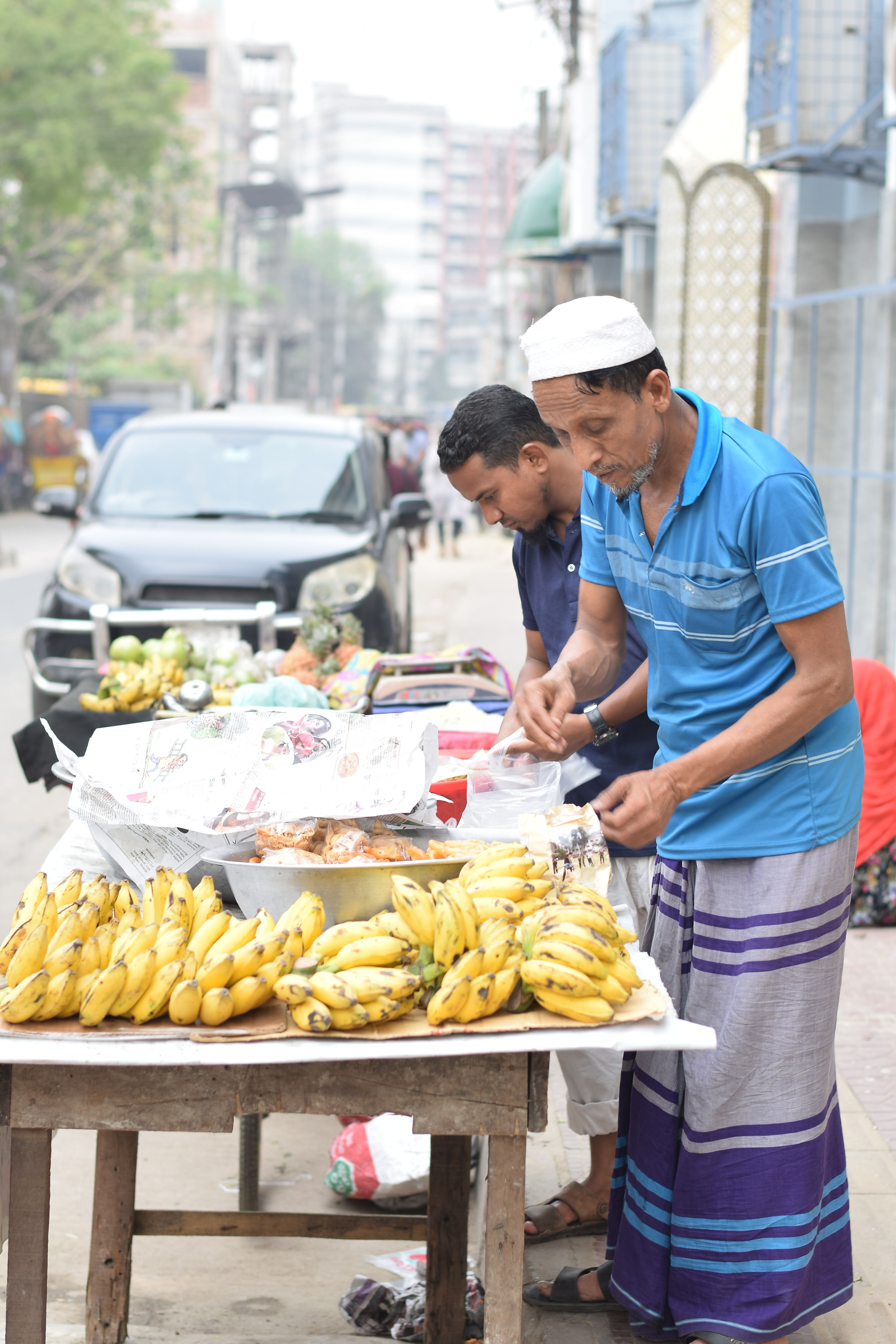 Two street vendors selling bananas and traditional food in Dhaka, Bangladesh.