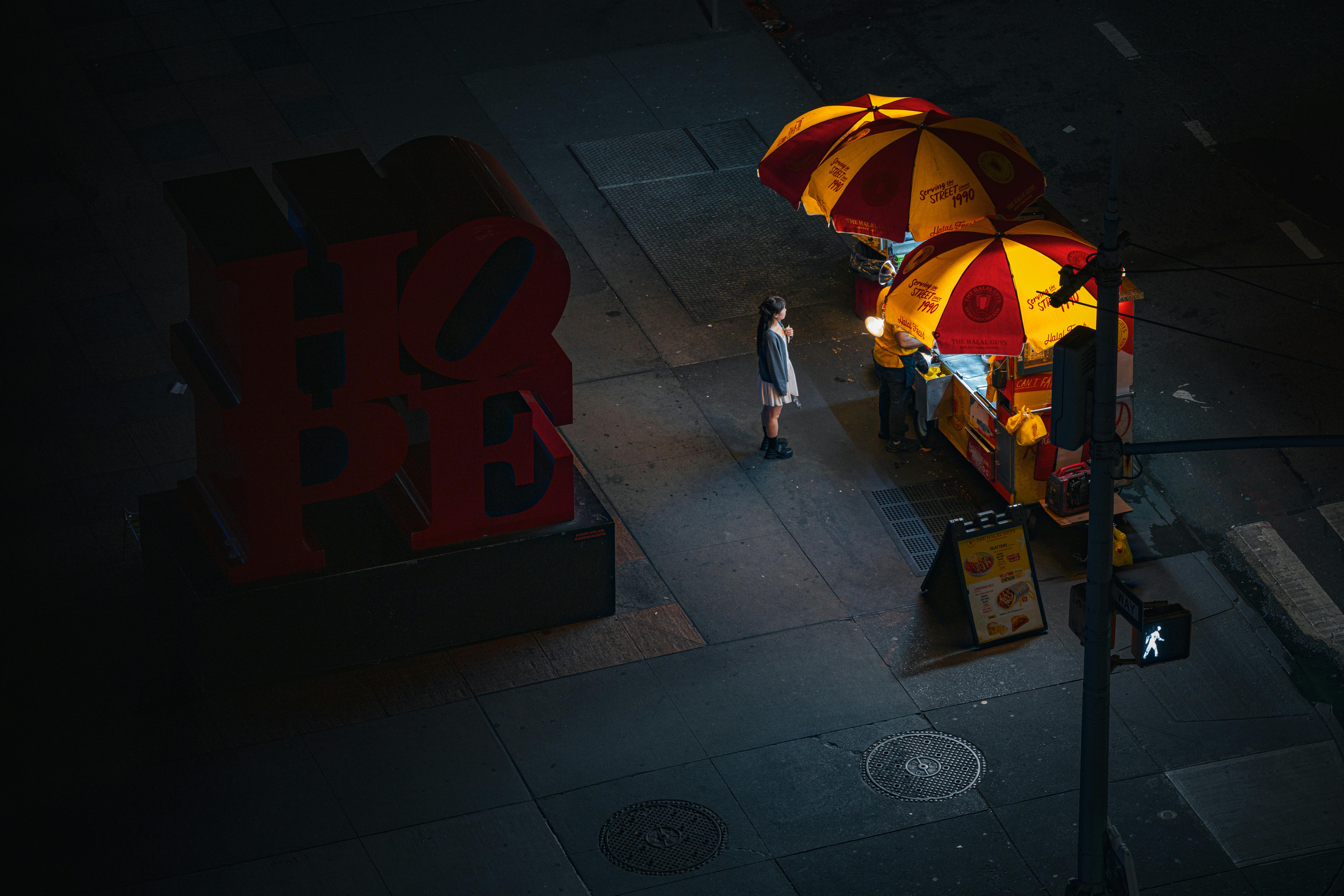 Gratis Luftfoto av en nattlig gatematselger i nærheten av HOPE-skiltet i New York City, som foreviger det pulserende bylivet. Arkivbilde