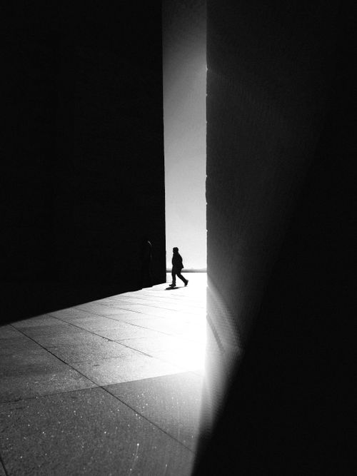 Free Black and white photo of a person walking through sunlight between tall walls in Çanakkale, Türkiye. Stock Photo