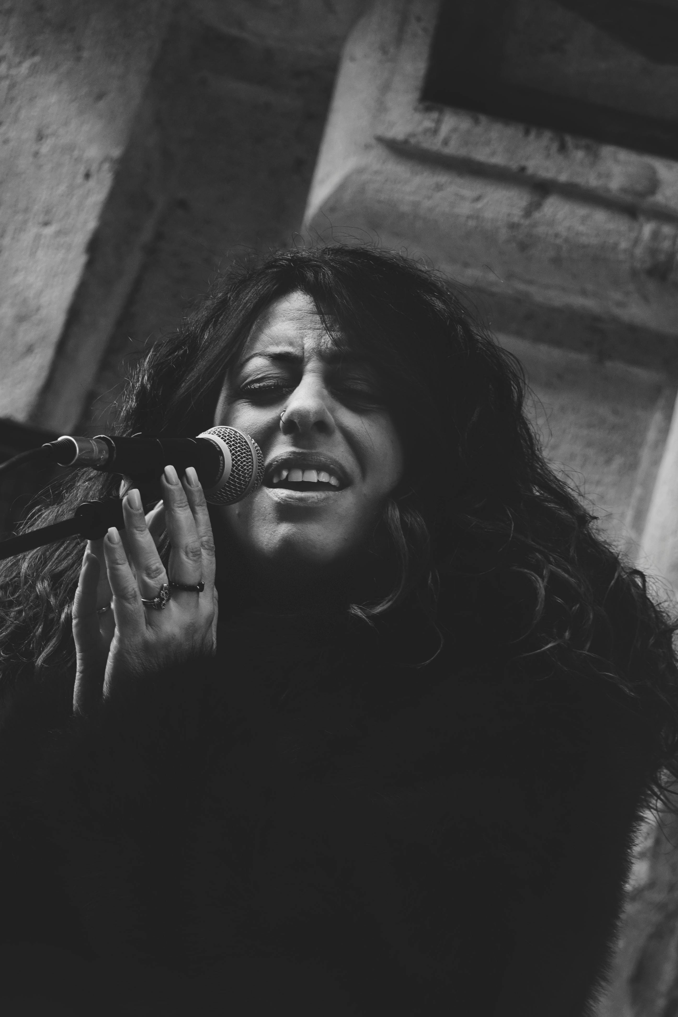 grátis Retrato artístico em preto e branco de uma mulher cantando com paixão no palco. Foto profissional