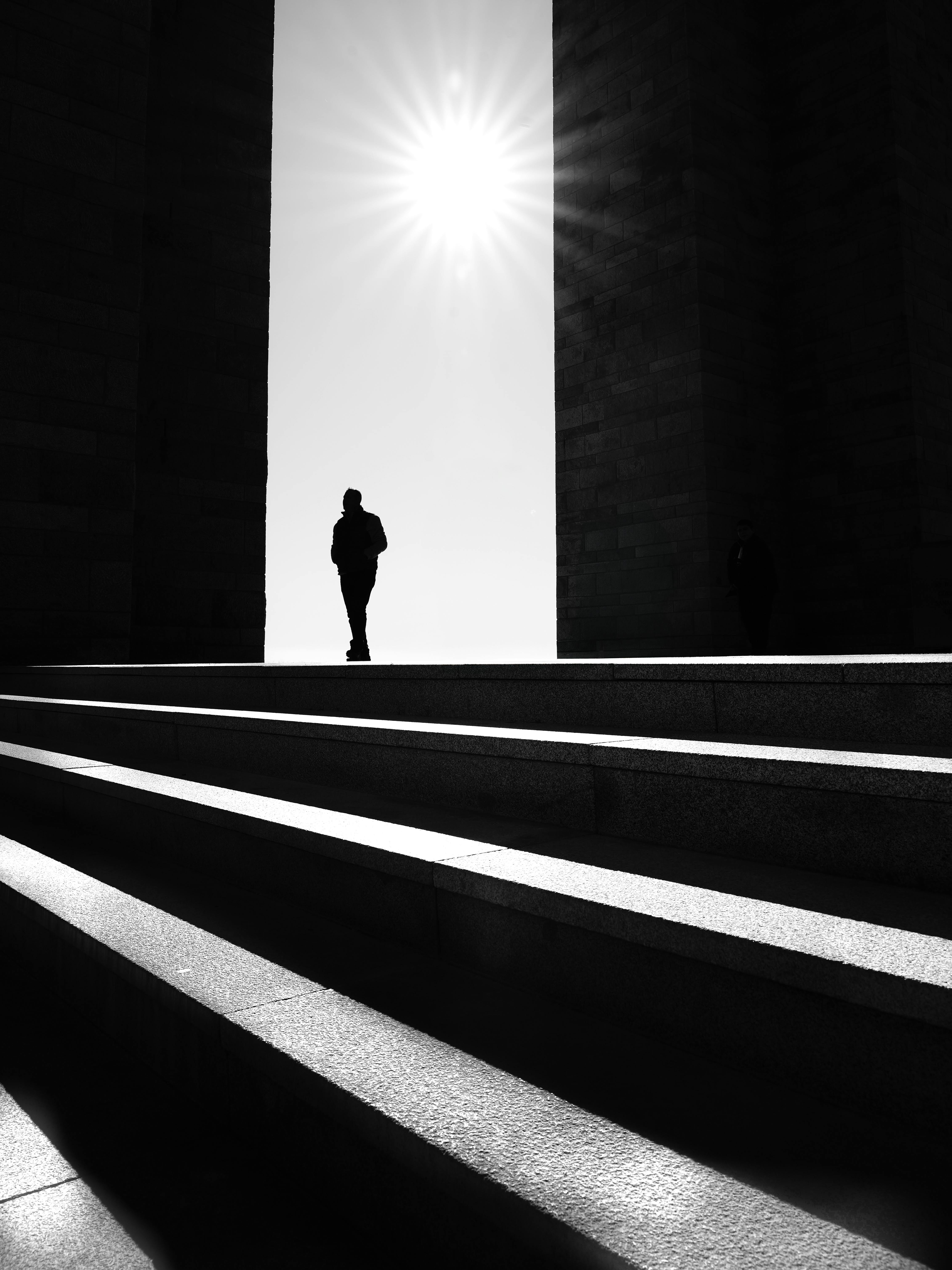 Kostenlos Schwarz-weiße Silhouette einer Person, die in Çanakkale, Türkei, vor hellem Sonnenlicht auf einer Treppe geht. Stock-Foto