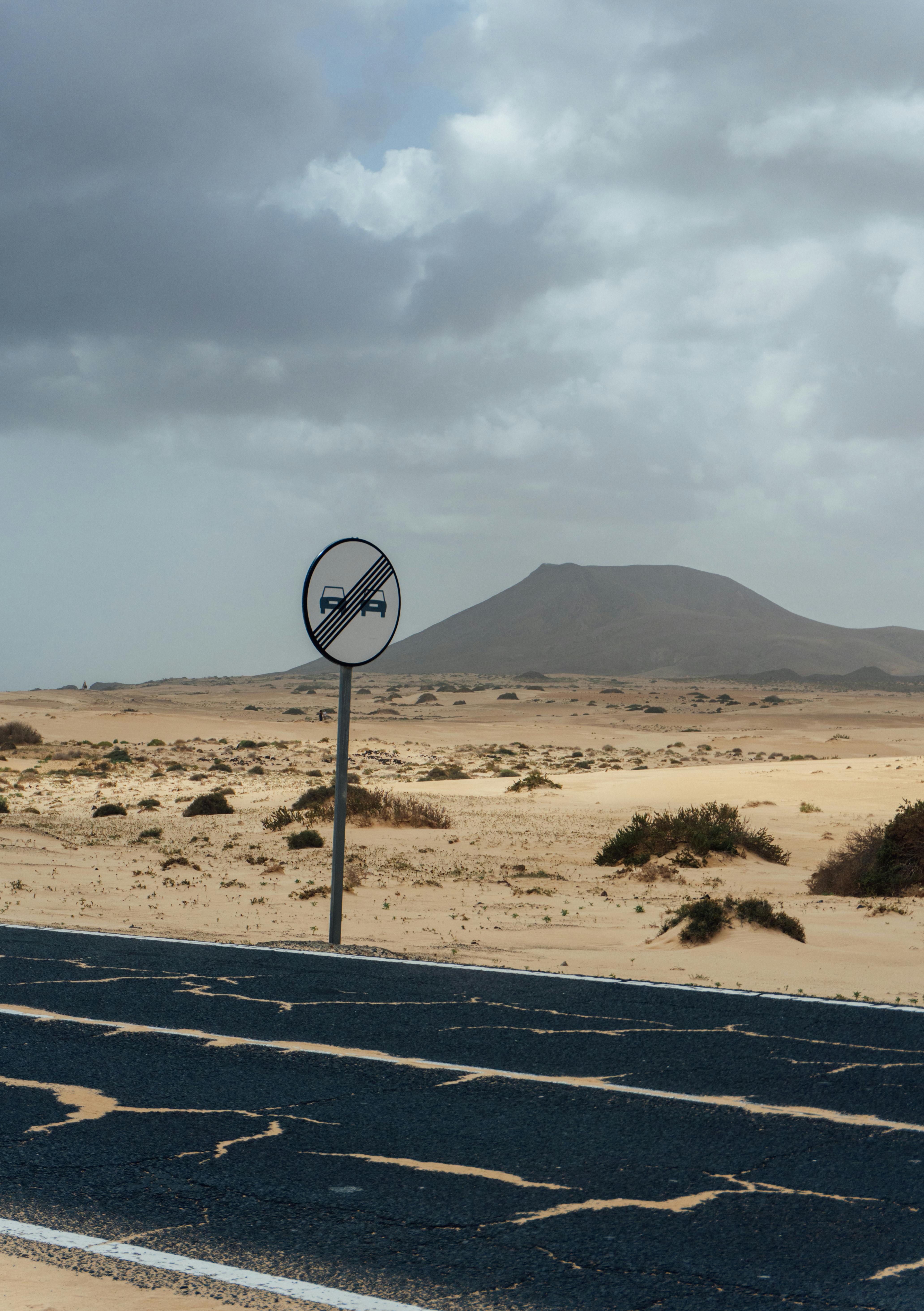 Bezpłatne Odludna droga na Wyspach Kanaryjskich ze znakiem zakazu ruchu pojazdów na tle górzystego krajobrazu pod zachmurzonym niebem. Zdjęcie z galerii