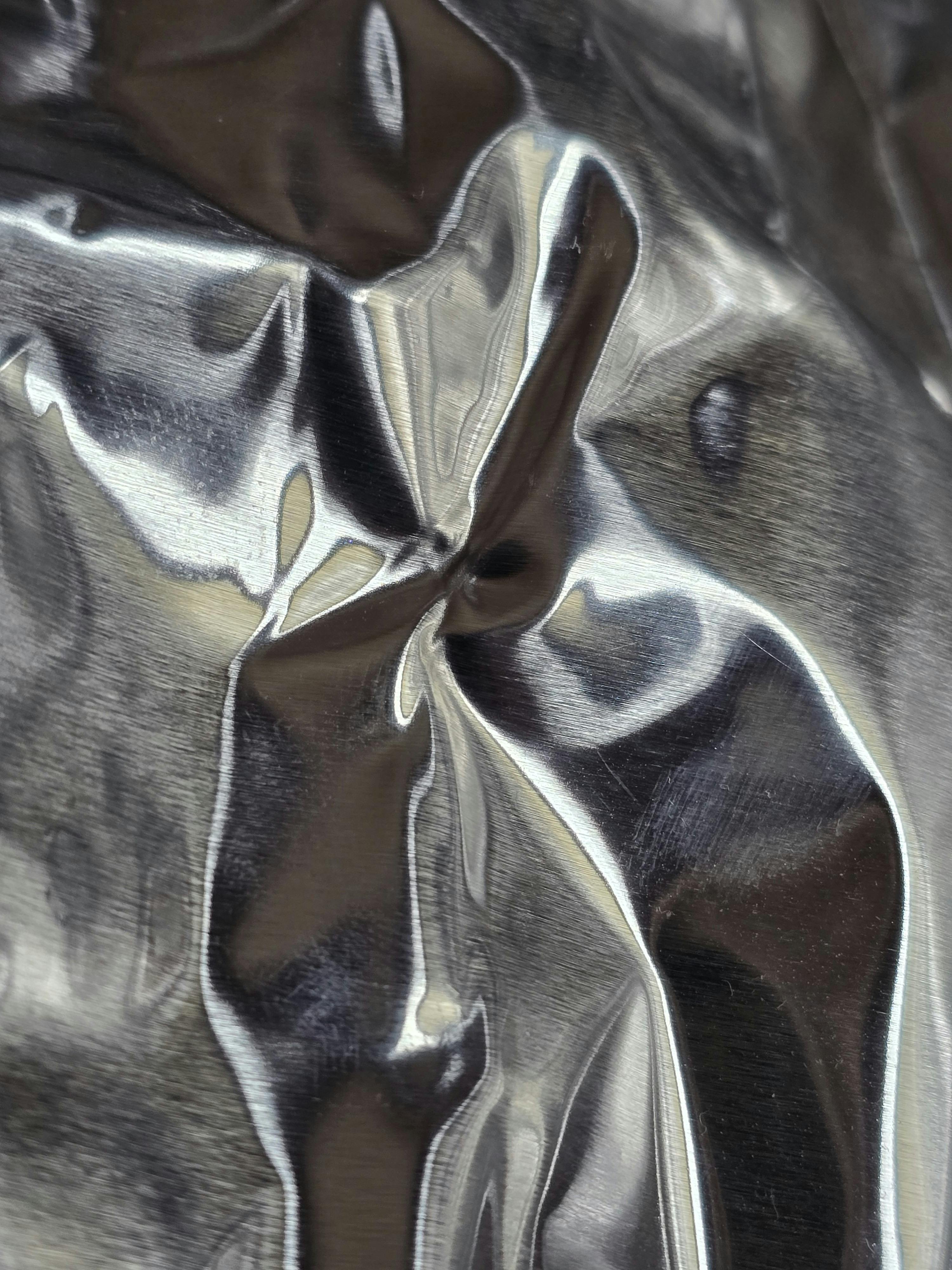 Gratis Primo piano dettagliato di un foglio di alluminio accartocciato che mette in risalto la texture e i riflessi metallici. Foto a disposizione