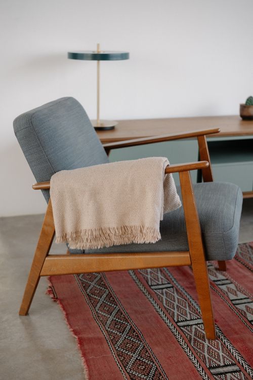 Free Stylish mid-century chair with a throw blanket indoors, fostering a cozy atmosphere. Stock Photo