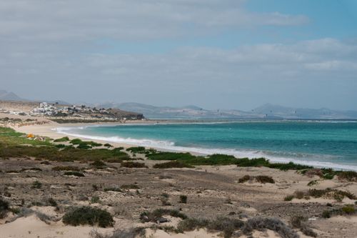Free Beautiful landscape of a coastal area with turquoise ocean, sandy beach, and distant mountains. Stock Photo