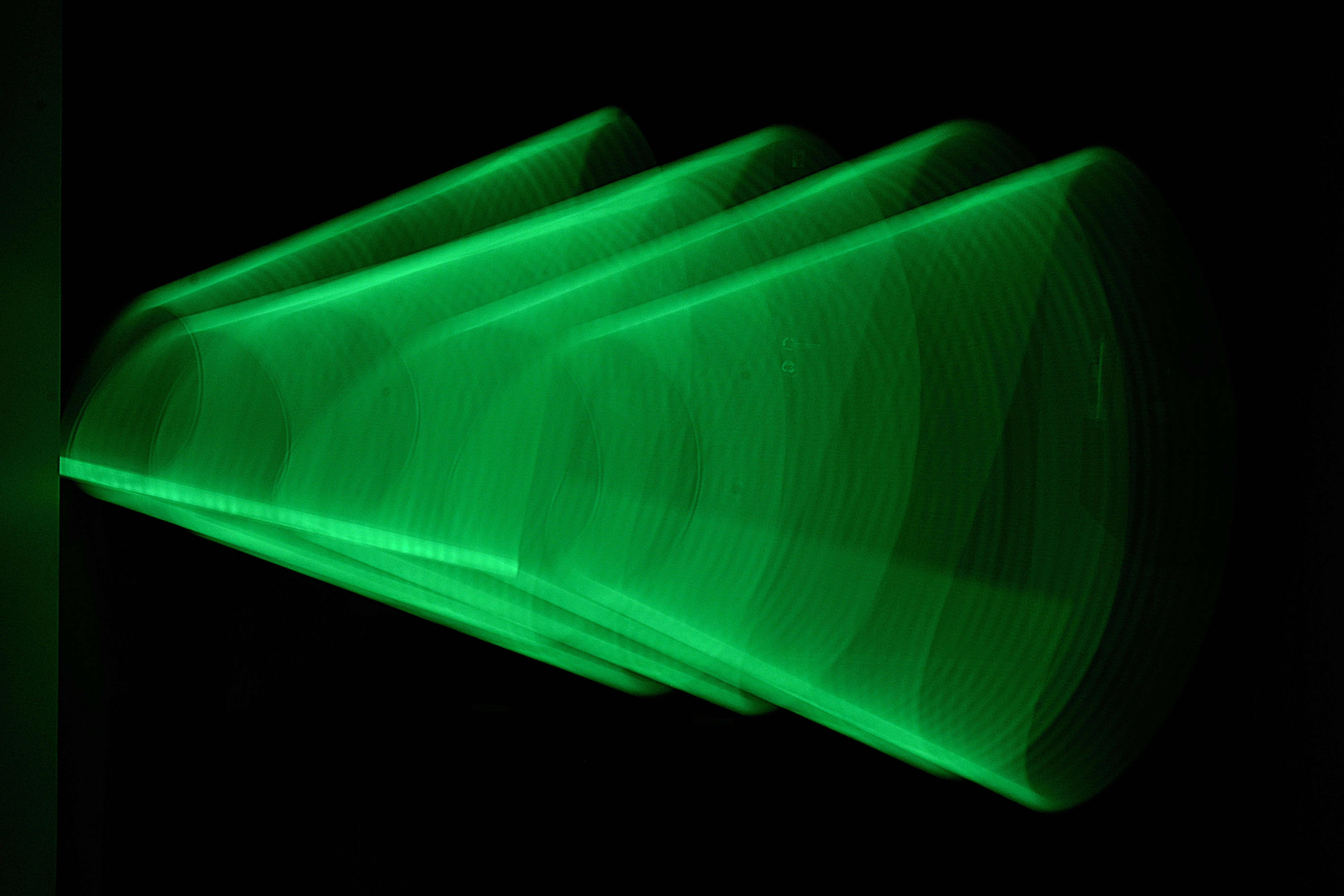 Kostnadsfria Dynamiskt abstrakt grönt ljusmönster fångat i rörelse mot en svart bakgrund, vilket skapar en modern konstnärlig effekt. Stock foto