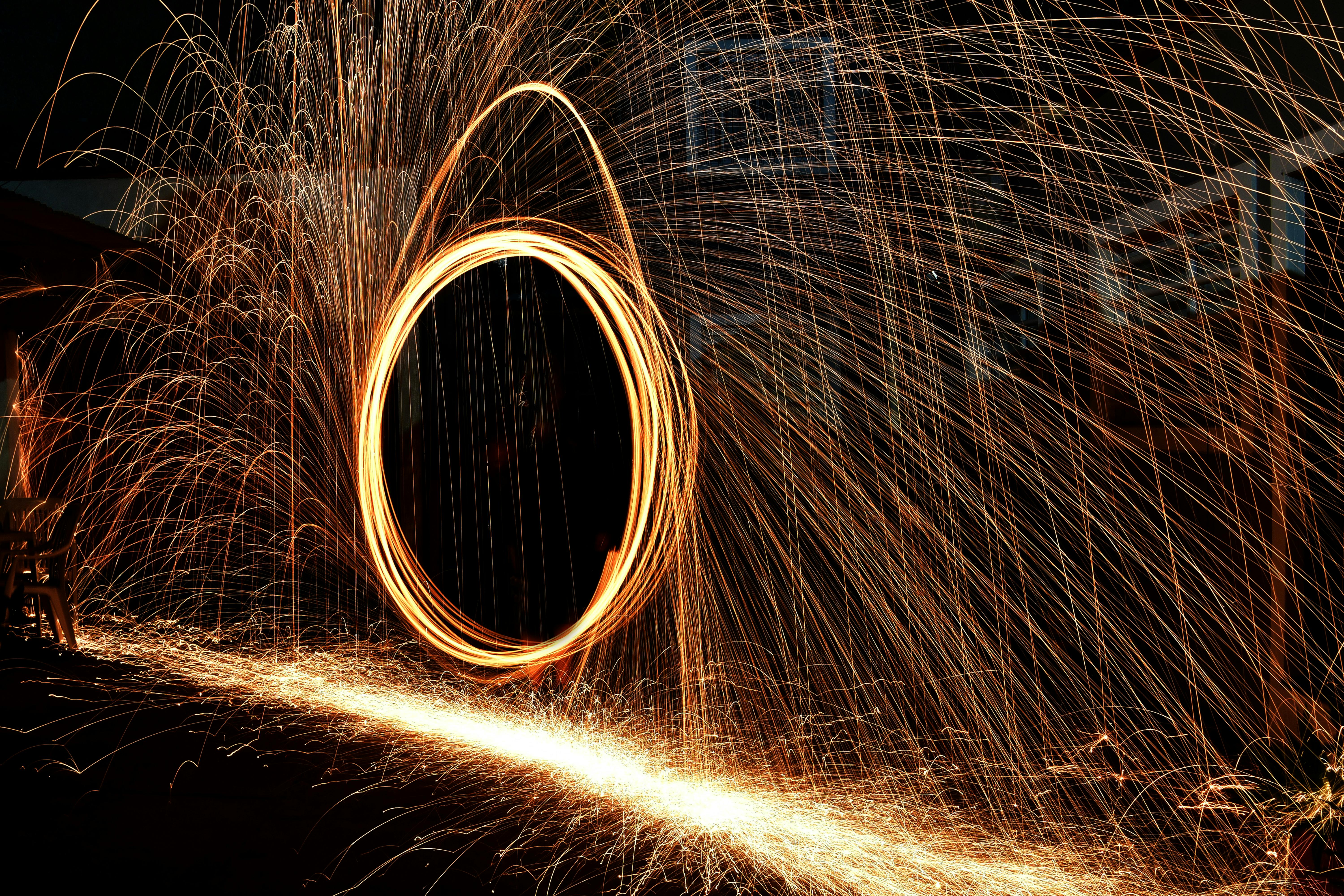 бесплатная Ослепительное зрелище света и движения, запечатленное в ночи с помощью искр стальной ваты. Стоковое фото