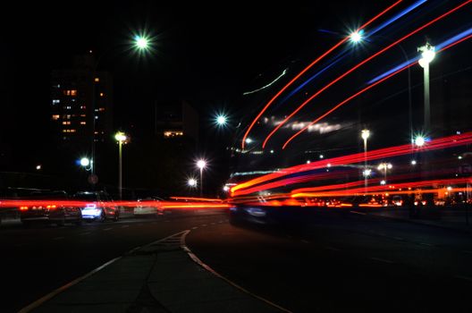 Vibrant long exposure photograph capturing light trails of a busy urban street at night.