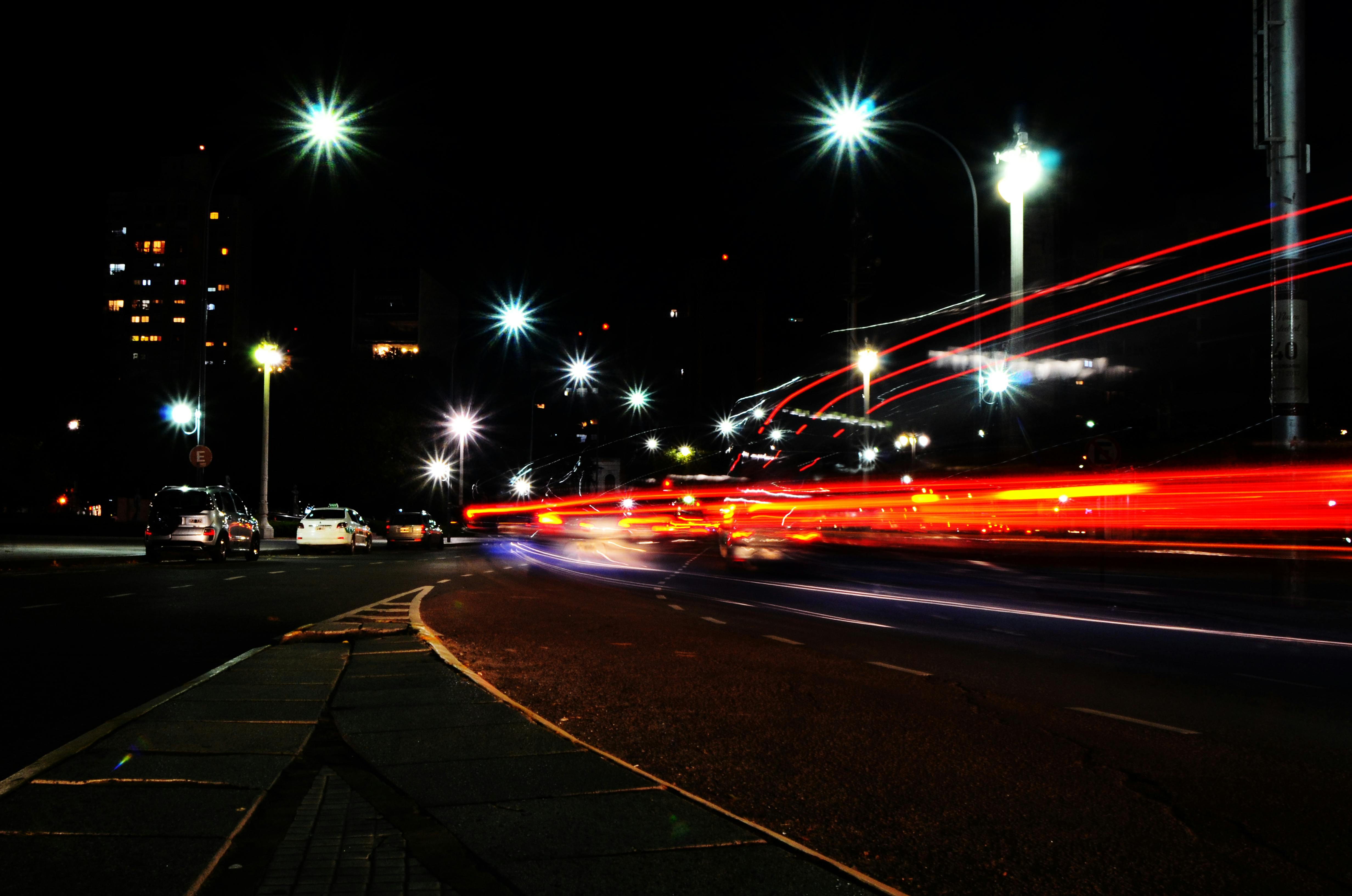 無料 活気あふれる街路に鮮やかな車のライトの軌跡が映し出される、ダイナミックな都市の夜景。都会の活気を捉えている。 写真素材