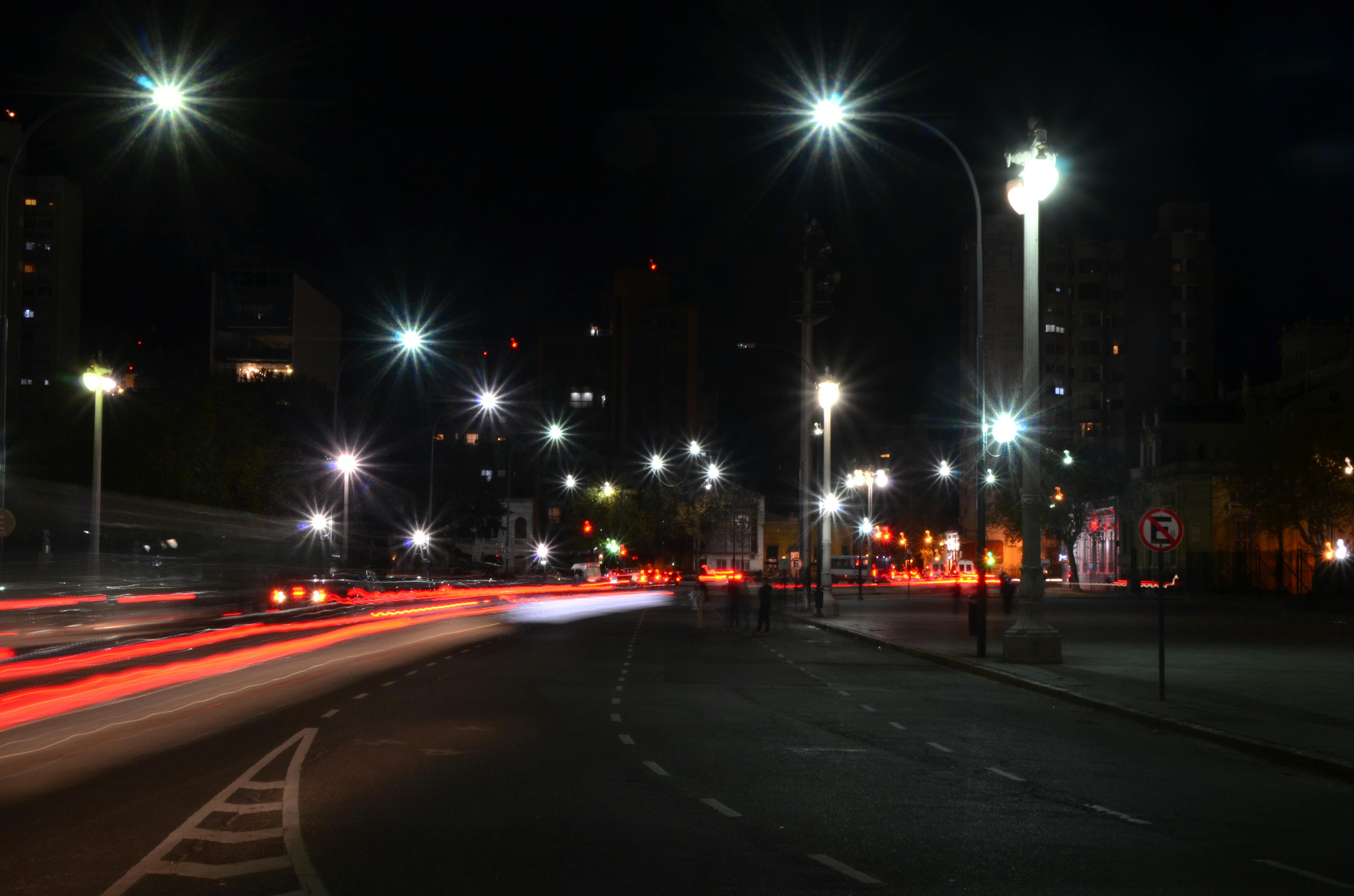 Gratis Calle de la ciudad por la noche, con estelas de luz de larga exposición y farolas encendidas. Foto de stock