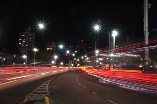 Dynamic night cityscape with vibrant car light trails on urban street.