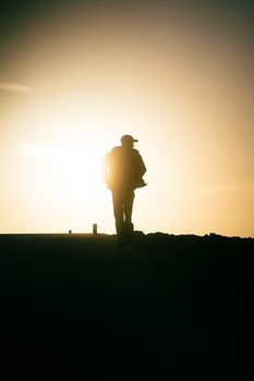 A silhouette of an individual jogging along the coastline during sunrise in Antalya, Türkiye.