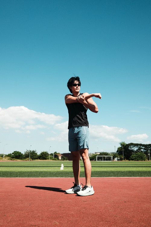 Free A man stretches his arms on an athletic track in Taytay, Philippines, under a clear blue sky. Stock Photo