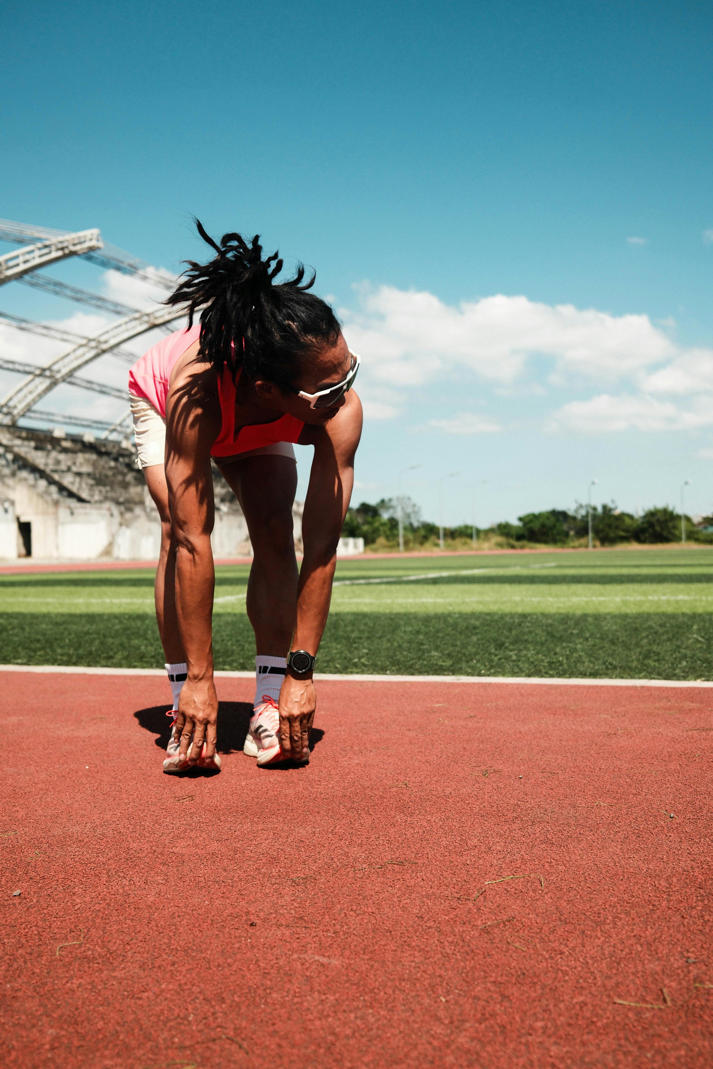 Athlete stretching on a track field under clear skies in Taytay, Philippines.