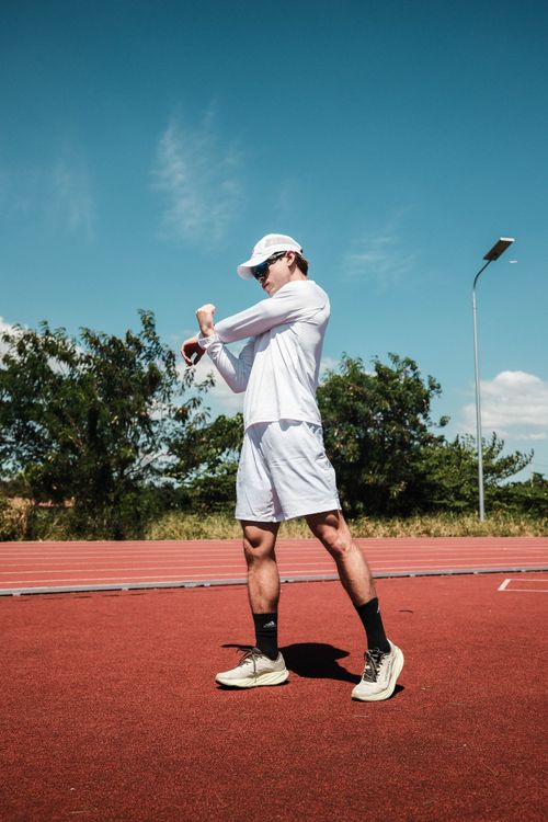 Free Young athlete stretching on a sunny day at an outdoor track in Taytay, Philippines. Stock Photo