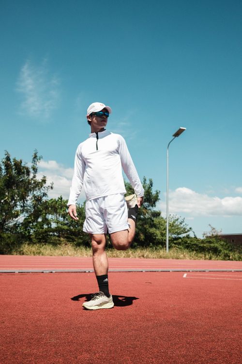 Free Athlete in sports attire stretching on an outdoor track in Taytay, Philippines. Stock Photo