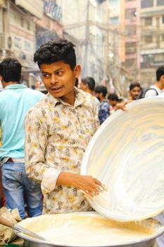 A street food vendor mixes ingredients at a bustling bazaar in Dhaka, Bangladesh.