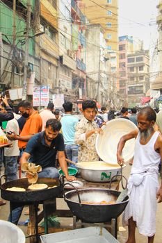 Street vendors prepare traditional foods in a bustling Dhaka bazaar.