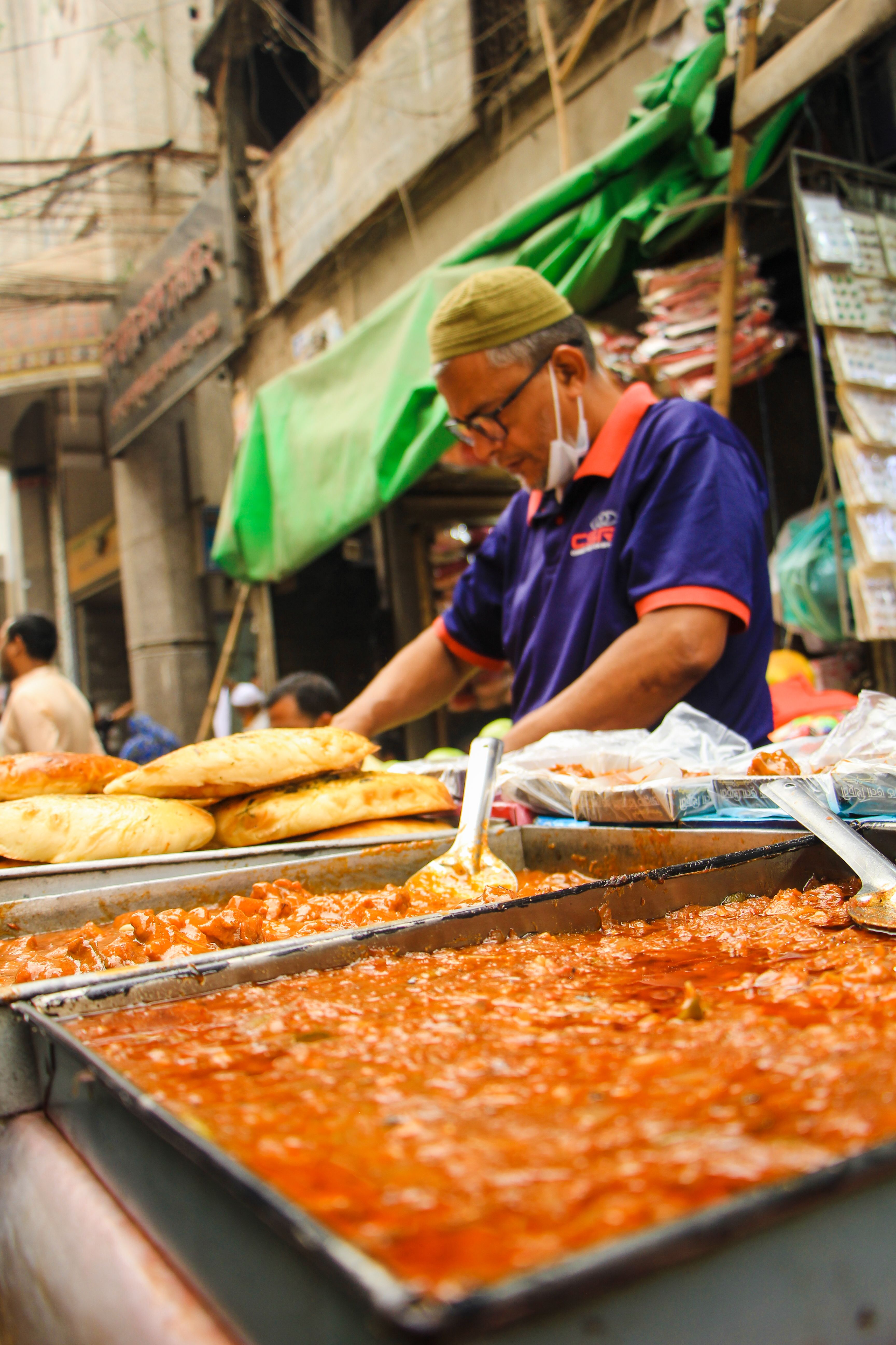 Street vendor in Dhaka setting up traditional iftar food market display during Ramadan.