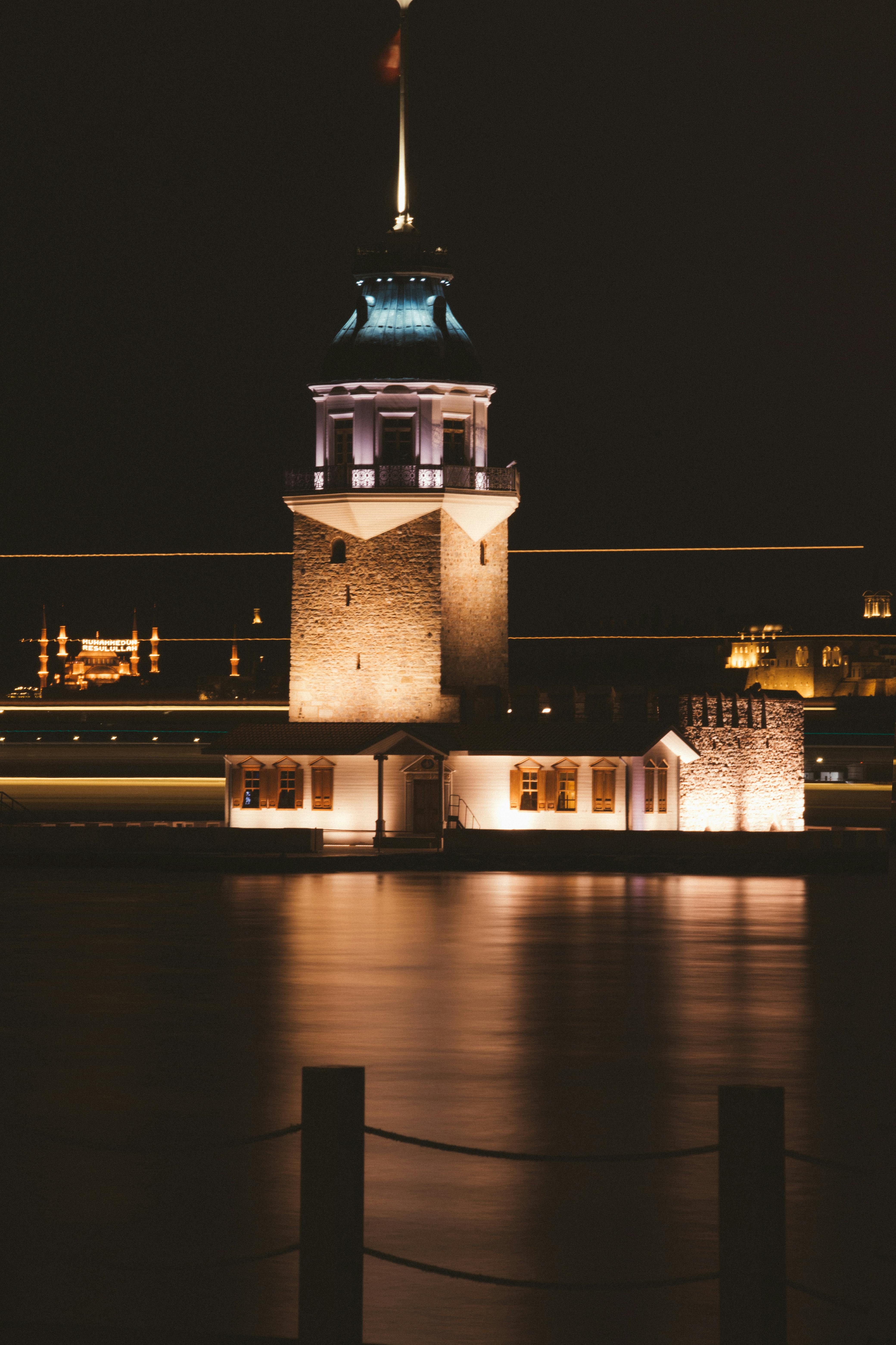 Gratis Vakker lang eksponering av Jomfrutårnet i Istanbul om natten, reflektert i rolig vann. Arkivbilde