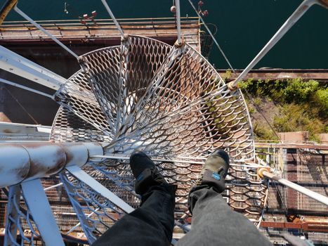 Experience the thrill of heights with this aerial view of a metal staircase over an industrial site.