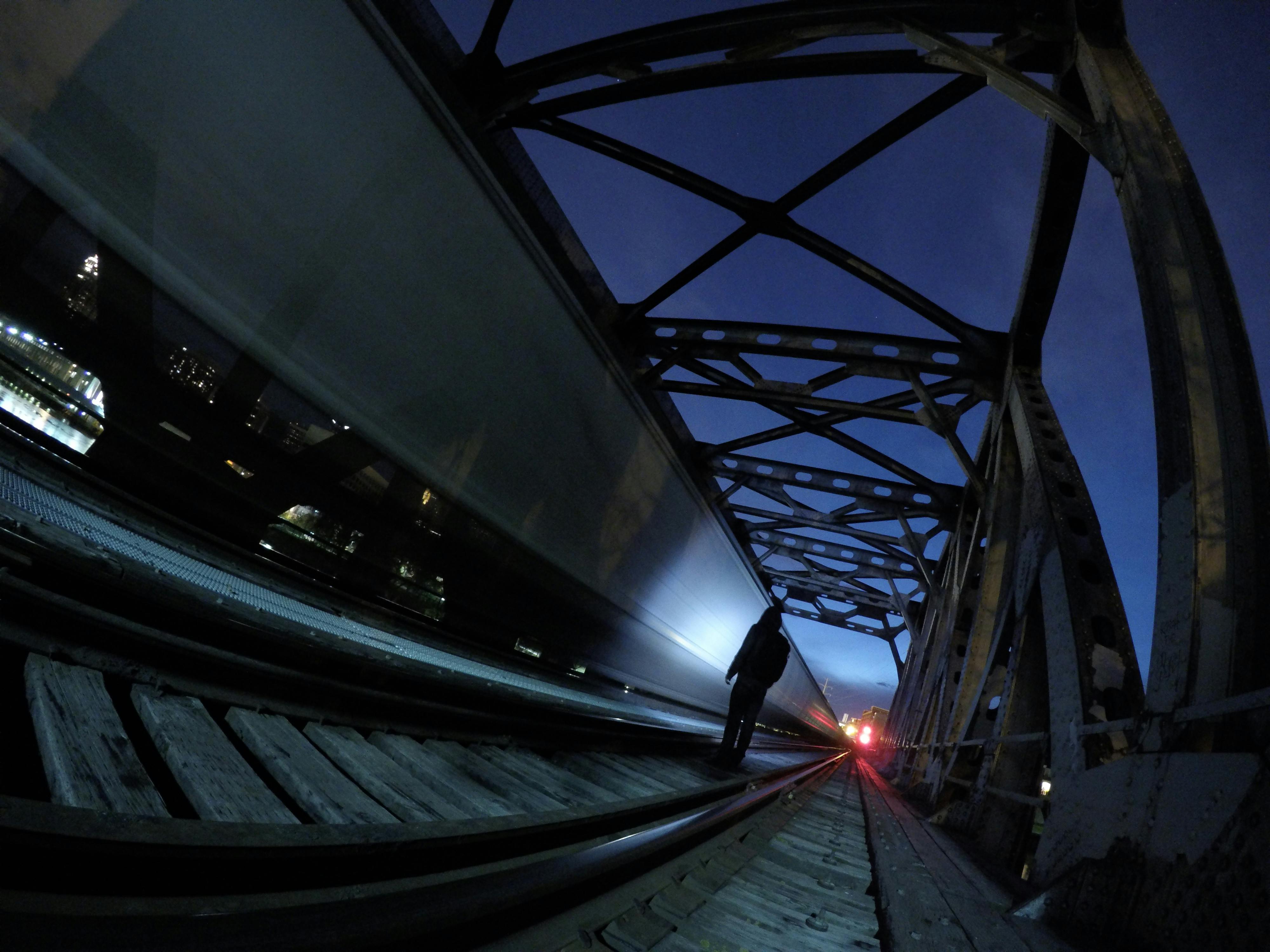 Gratuit Photo nocturne à longue exposition d'un train circulant sur un pont avec une silhouette humaine. Photos