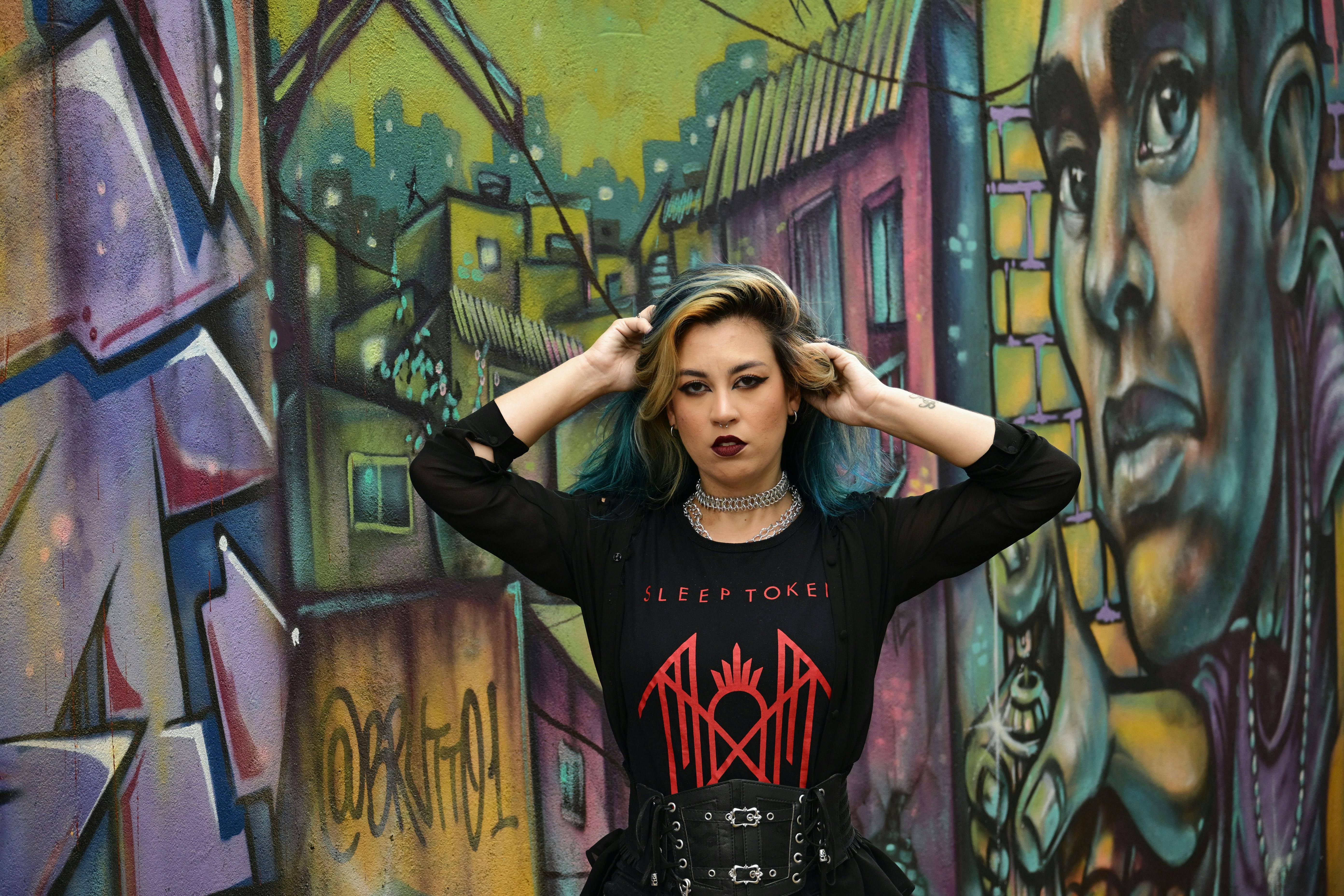 Gratis Mujer con estilo atrevido posando frente a un colorido muro de grafitis urbanos. Foto de stock