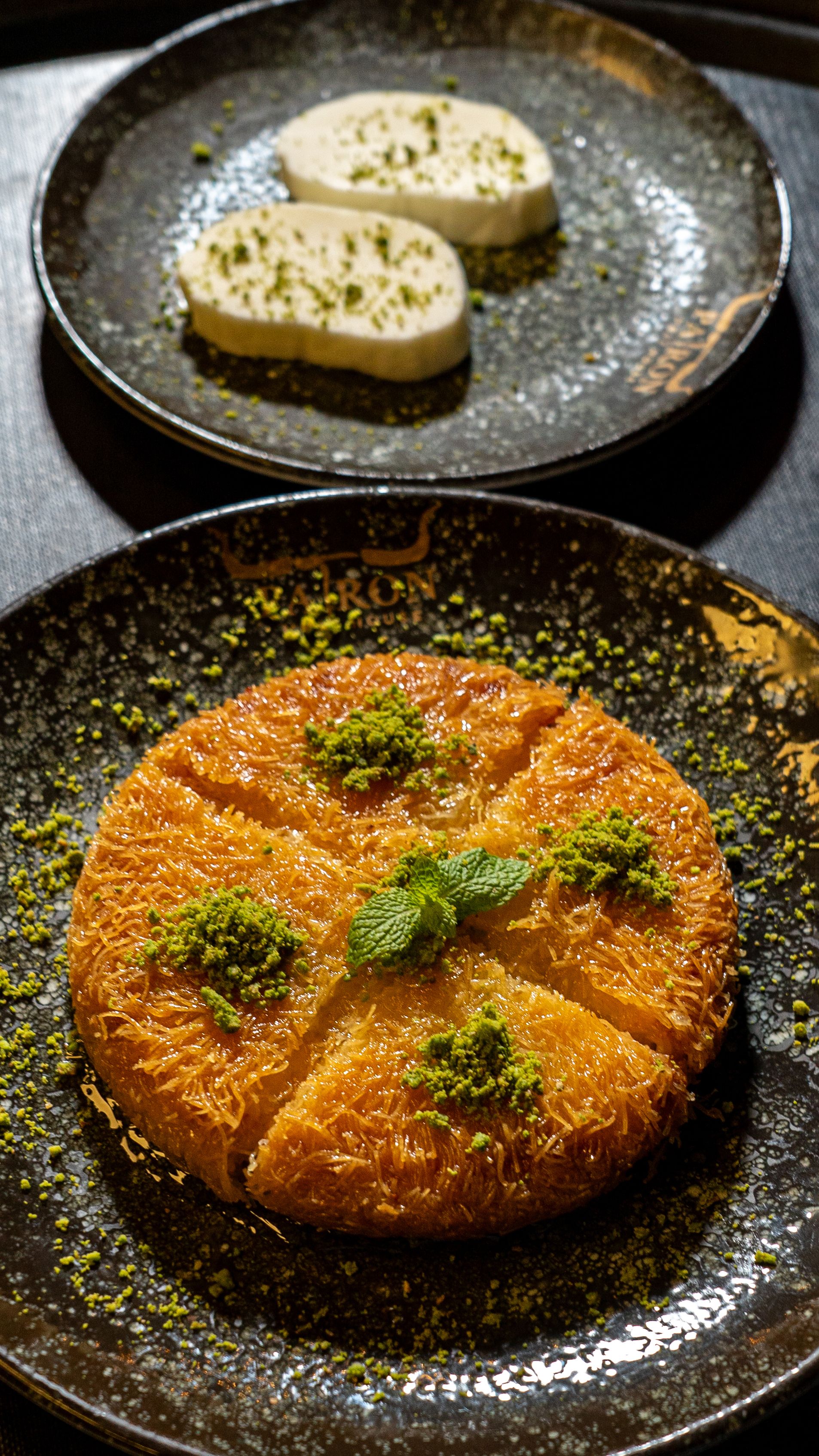 An appetizing plate of traditional kunafeh topped with pistachio and served with ice cream.