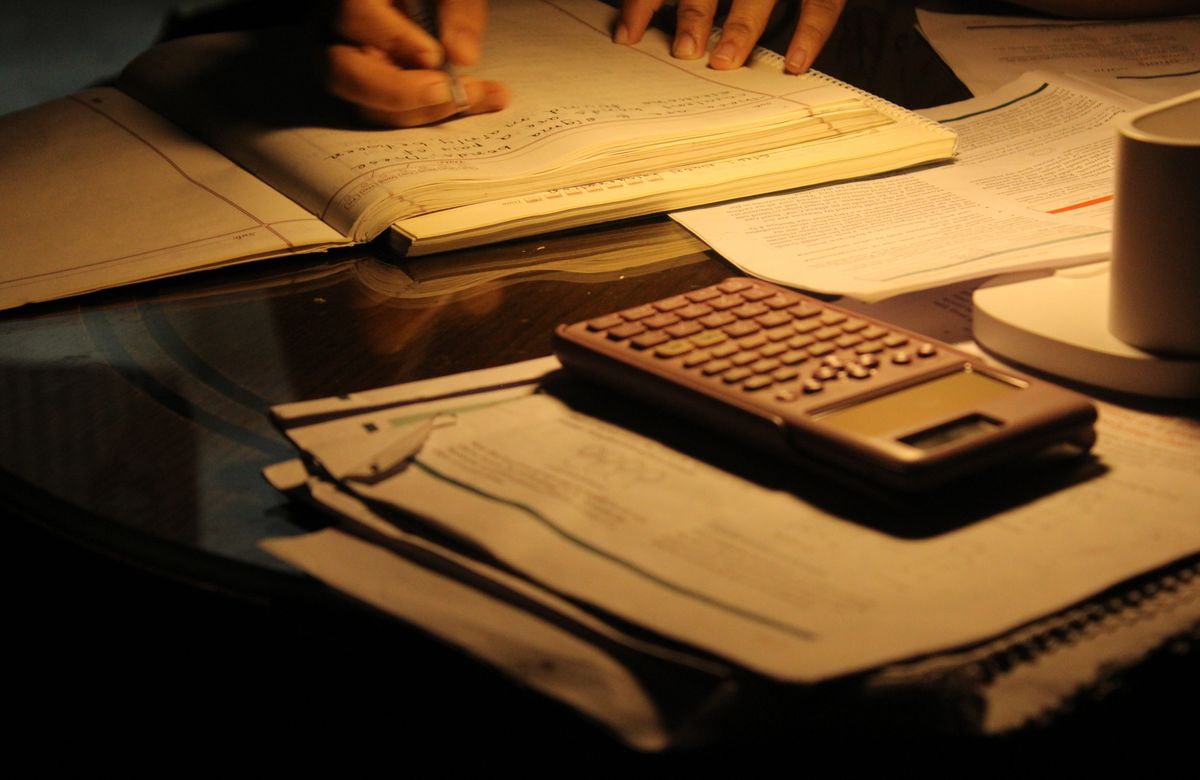 A focused study session at night with open books and a calculator on a dimly lit table